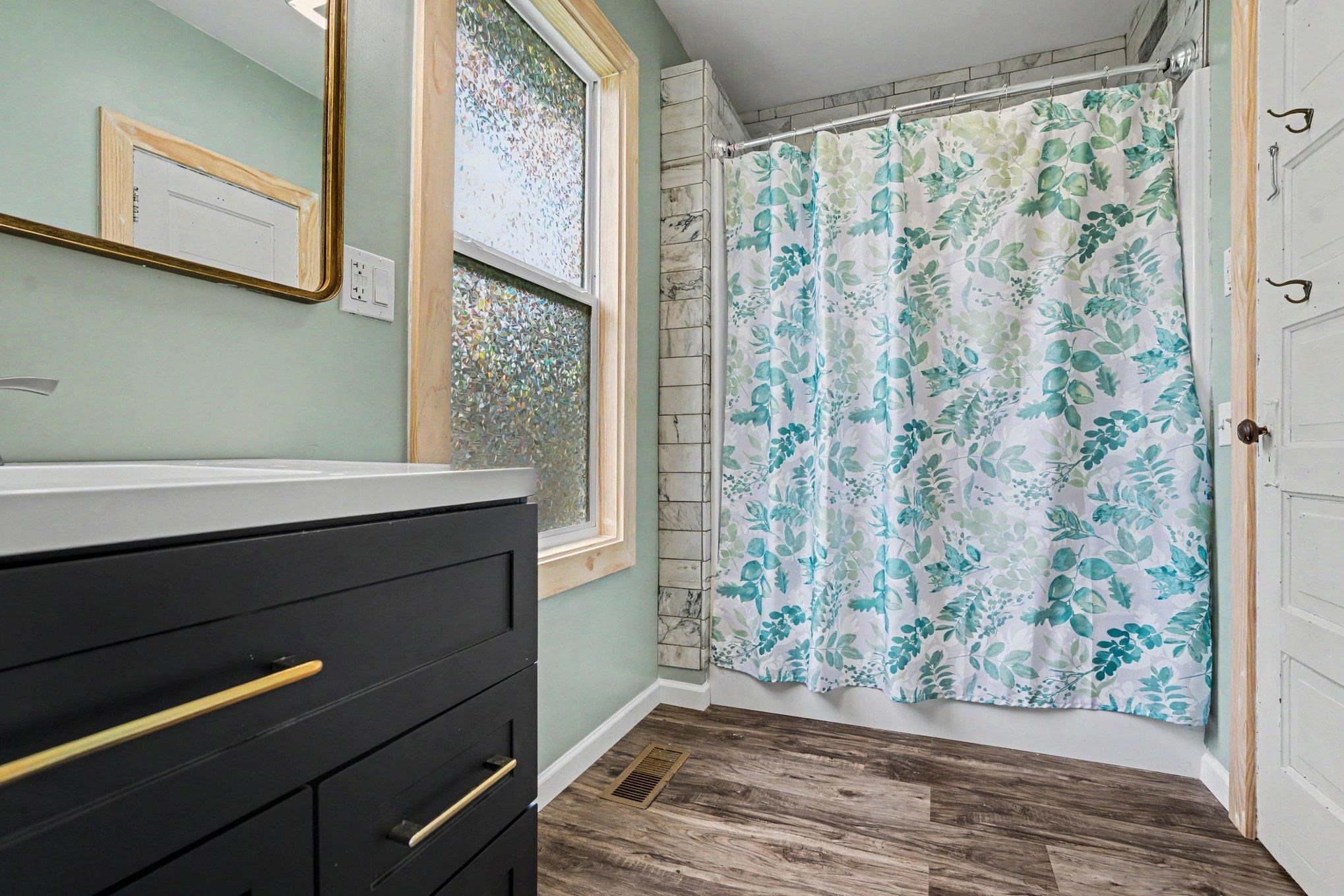 Bathroom featuring a dark vanity with gold-tone hardware, a white countertop, and a rectangular sink