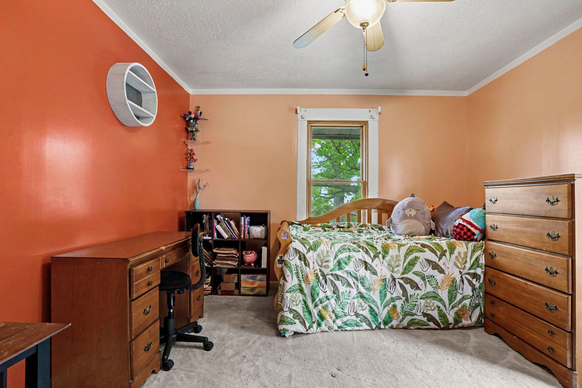 Carpeted room with a ceiling fan, a window with white trim, and a built-in bookshelf