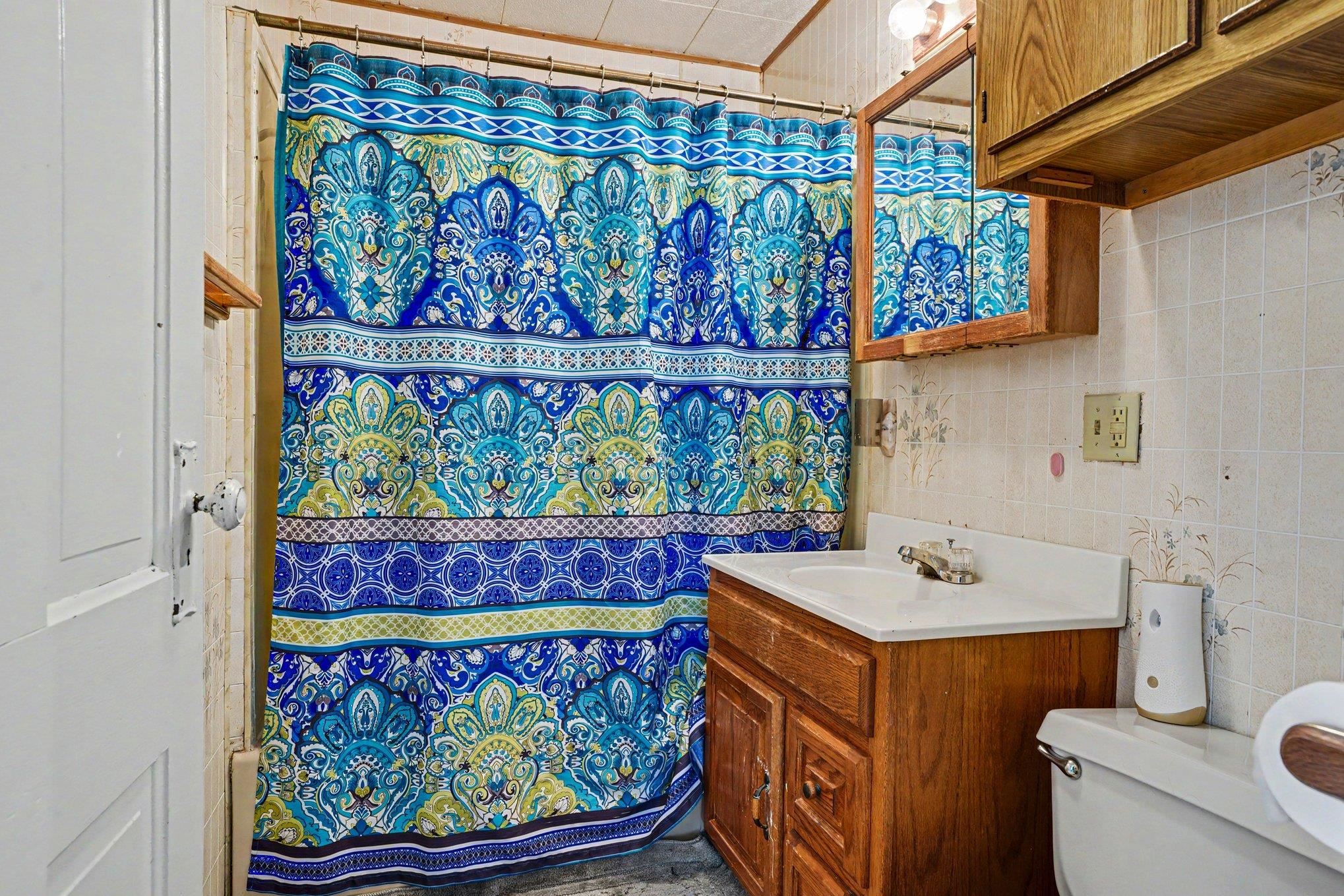 Bathroom featuring a white vanity with a built-in sink, wood-finish cabinetry, and a mirrored medicine cabinet