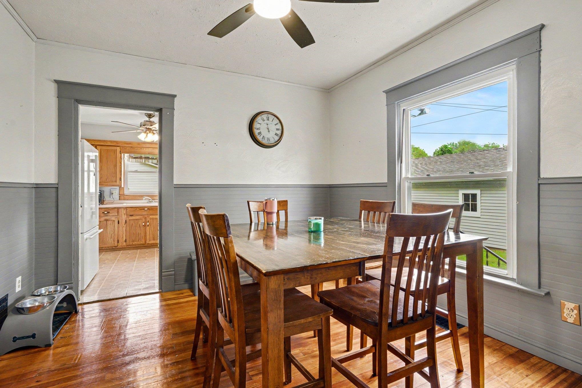 Dining area featuring wood-finish flooring, a ceiling fan, and a single window with gray trim