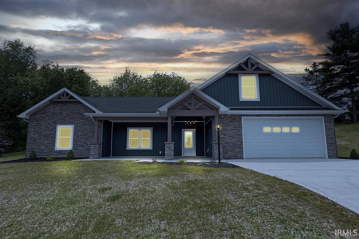 Stone facade and dark siding home featuring an attached garage, covered front porch, and concrete driveway