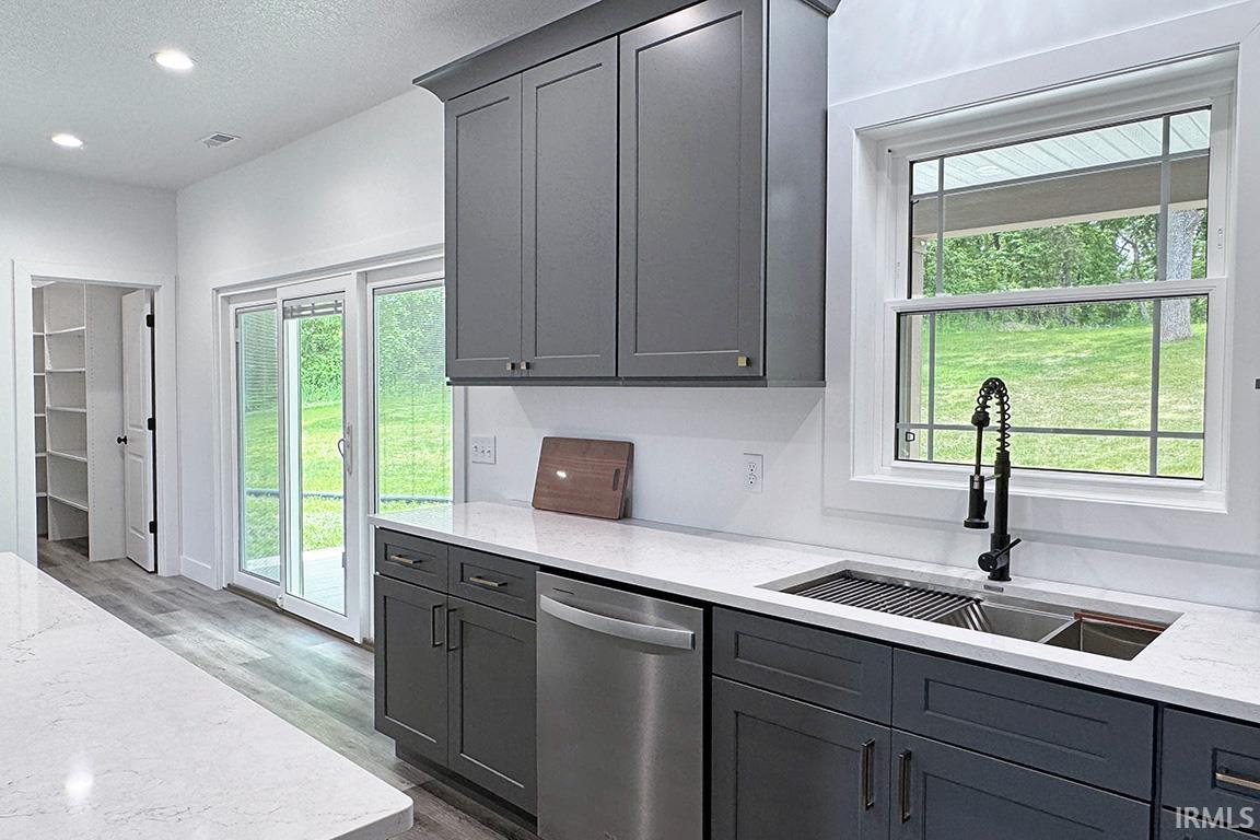 Modern kitchen featuring gray shaker-style cabinetry, white countertops, and wood-finish flooring
