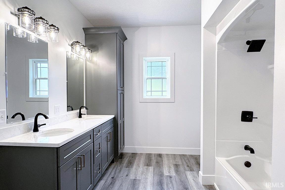 Bathroom featuring a dual vanity with gray cabinetry, white countertops, and matte black fixtures