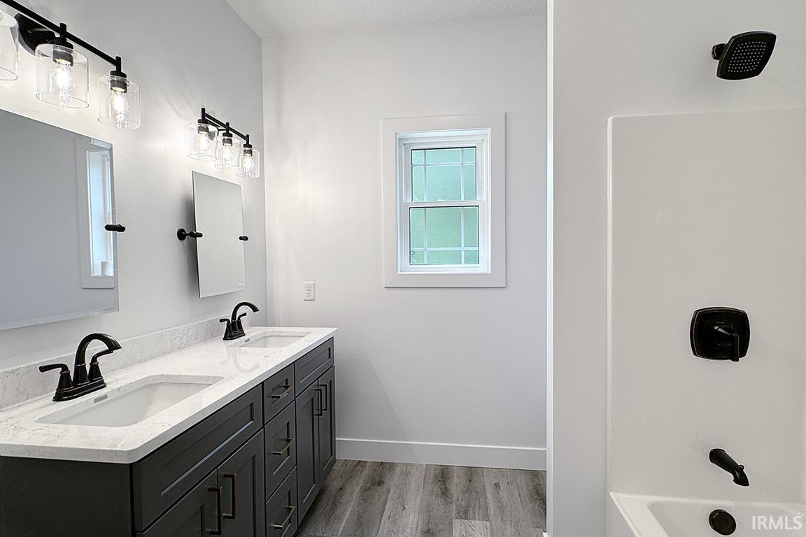 Bathroom featuring a dual vanity with dark cabinetry, white countertops, dual rectangular sinks, and matte black fixtures