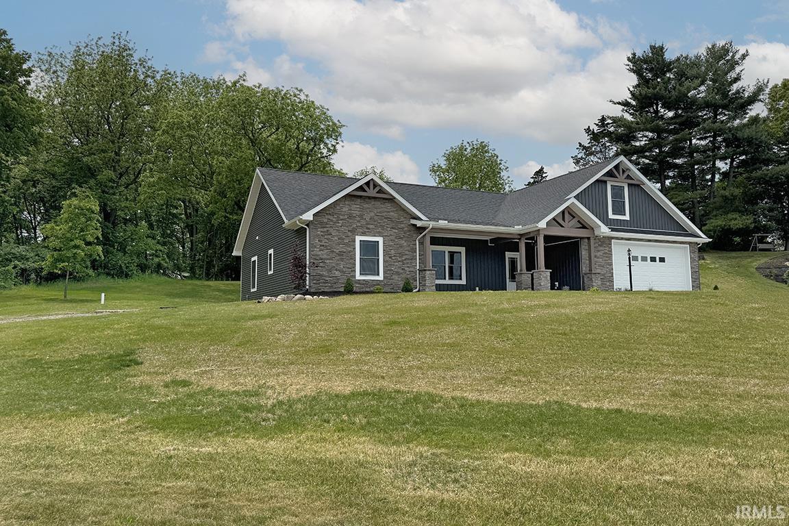 Contemporary residence featuring a stone and siding exterior, a prominent two-car garage, and an inviting covered porch with decorative wood-look beams