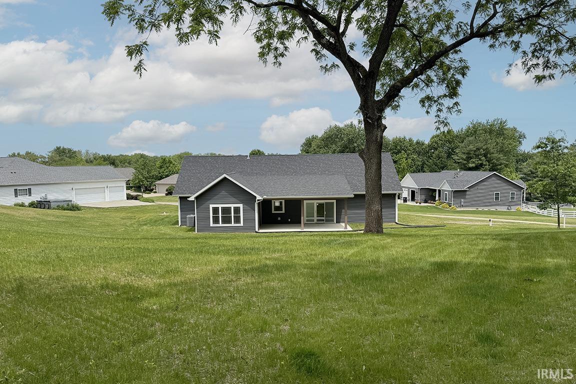 Contemporary gray siding home featuring a dark shingle roof, white trim windows, and a sliding glass door opening to a covered patio