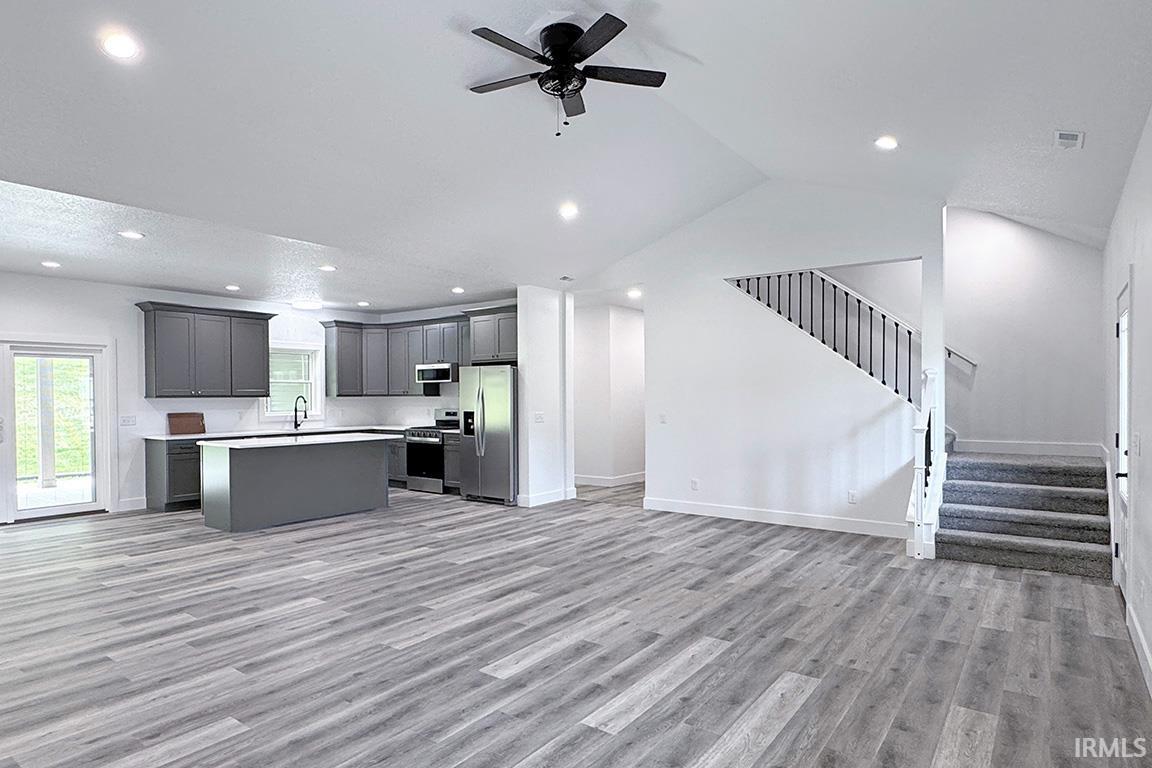 Open-concept living space featuring wood-finish flooring, recessed lighting, and vaulted ceilings