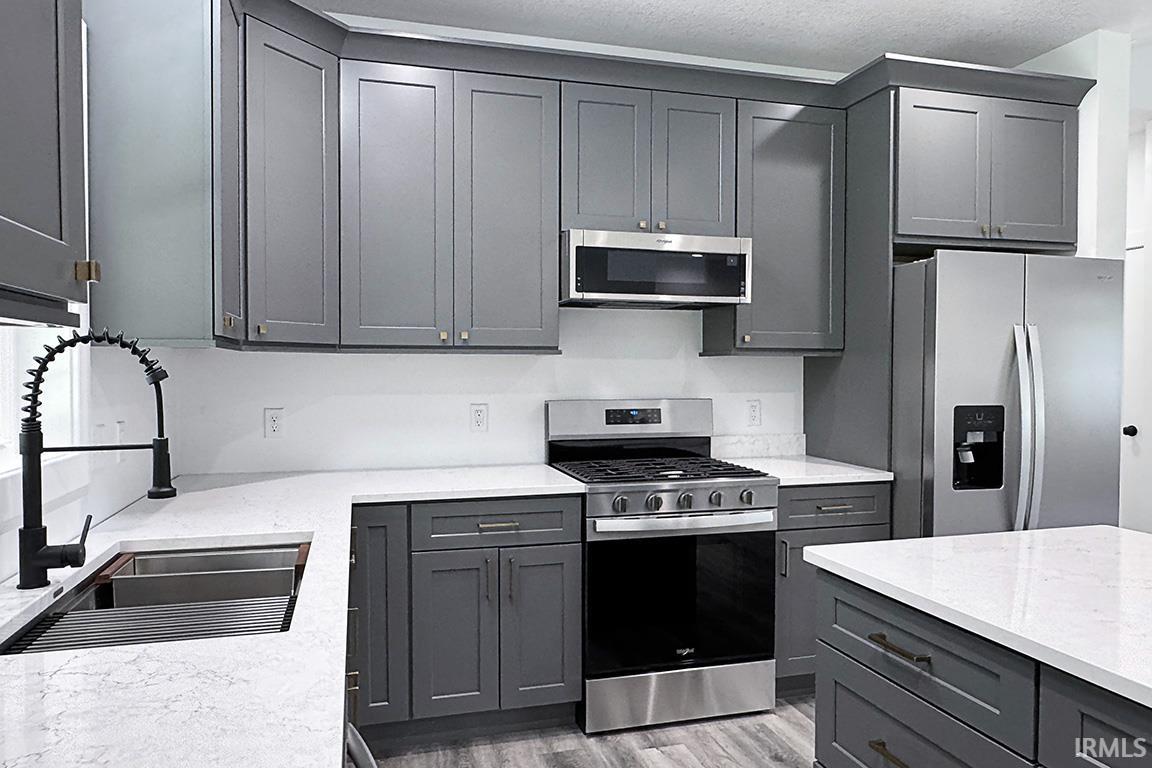 Contemporary kitchen featuring dark gray cabinetry, white countertops, and stainless steel appliances