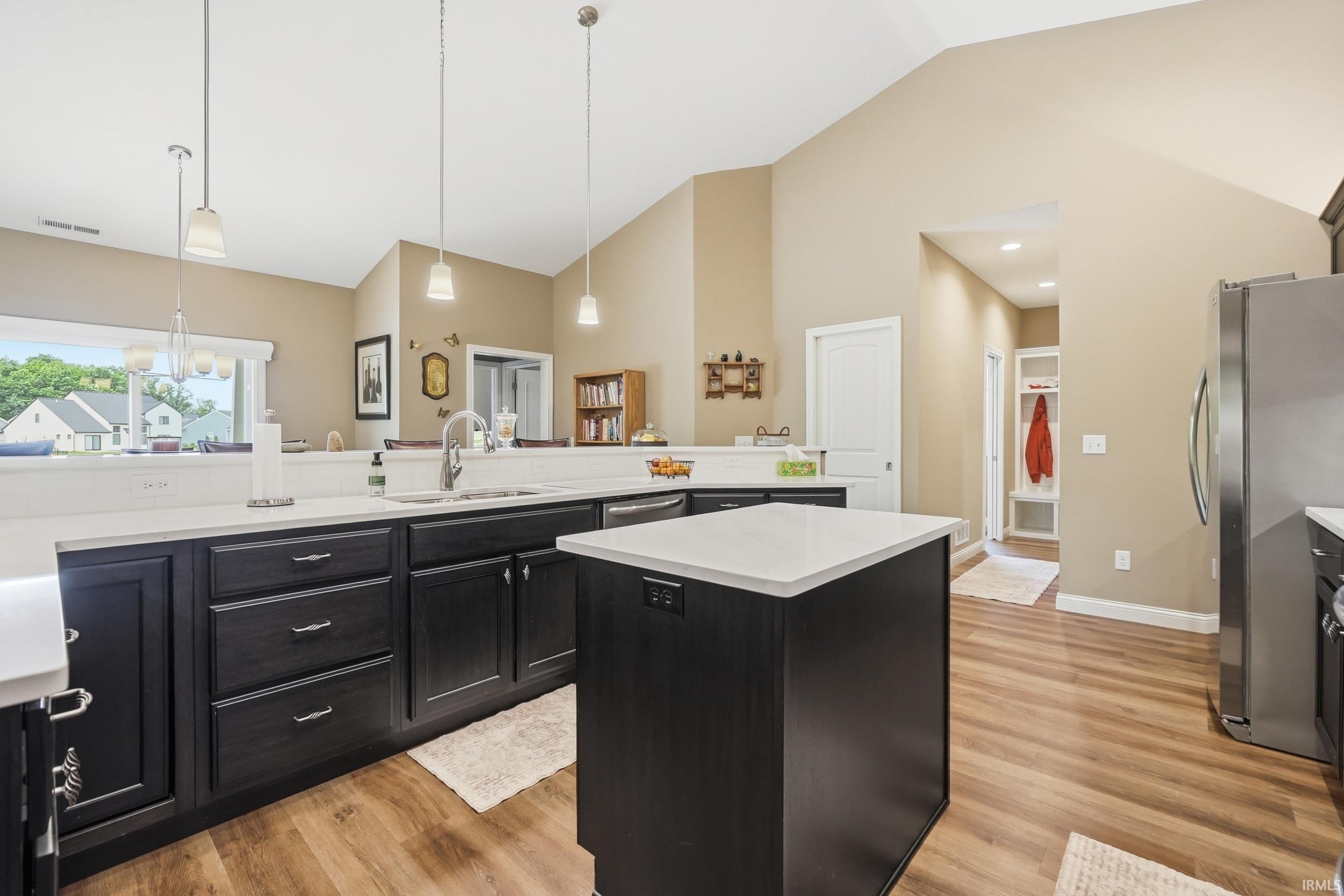 Kitchen featuring dark cabinetry, white countertops, stainless steel appliances, and wood-finish flooring