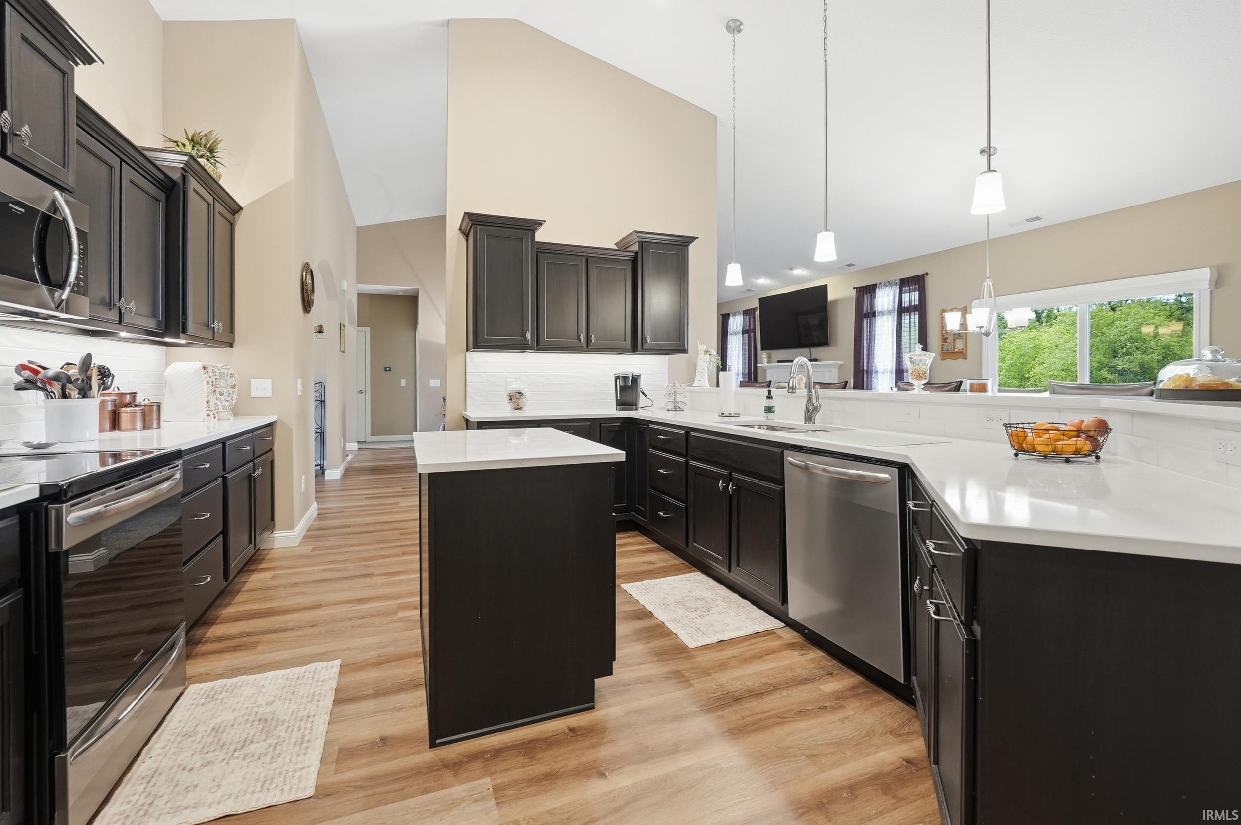 Kitchen featuring dark cabinetry, white countertops, stainless steel appliances, and wood-finish flooring