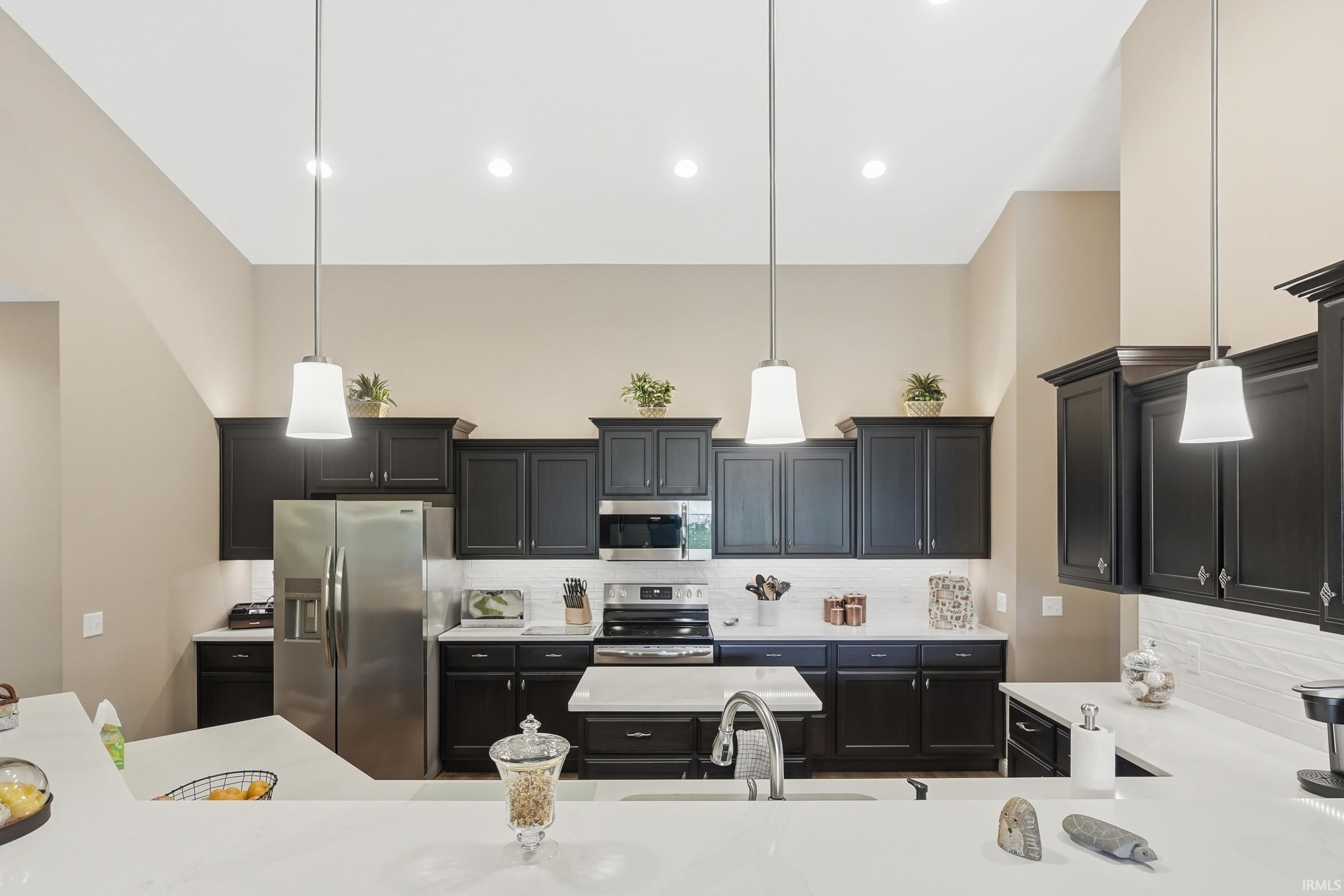 Kitchen featuring dark cabinetry with white countertops, stainless steel appliances, and a white subway tile backsplash