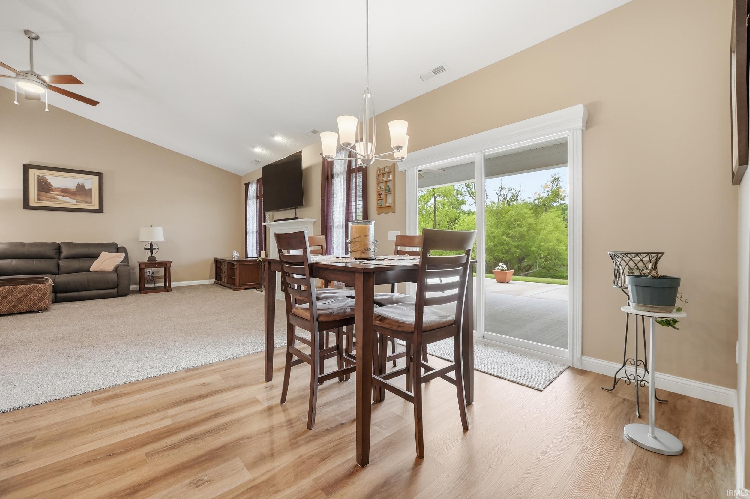 Open concept living space featuring wood-finish flooring, vaulted ceilings, and a sliding glass door leading to an outdoor patio