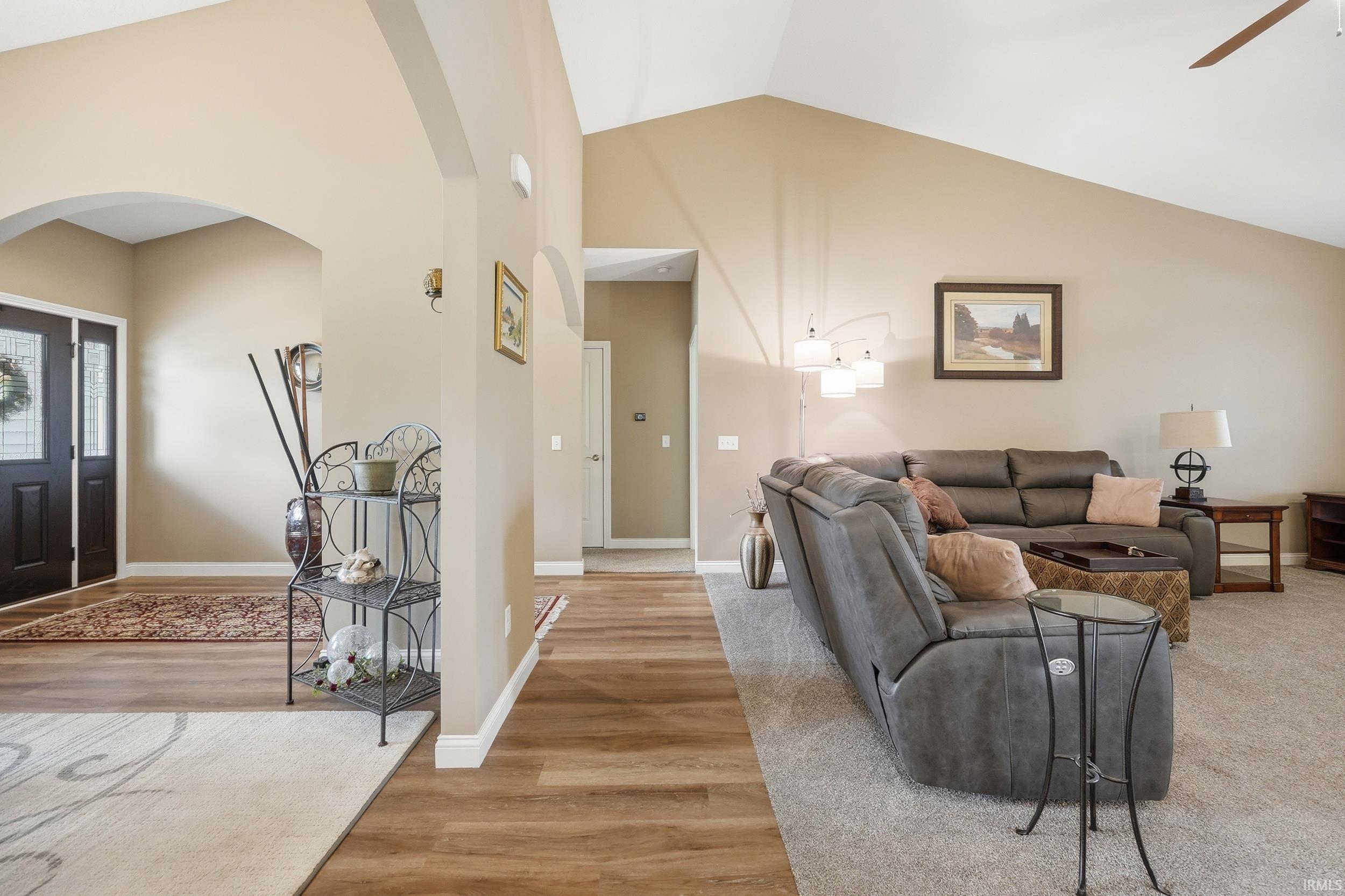 Vaulted ceiling living space with wood-finish flooring and neutral carpeting