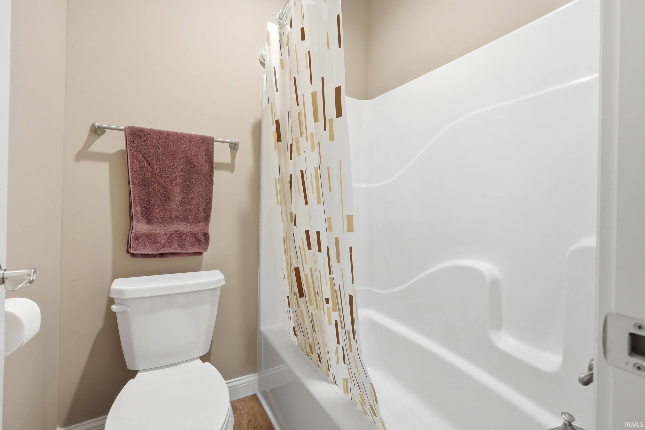 Bathroom featuring a white toilet and a white tub/shower combination