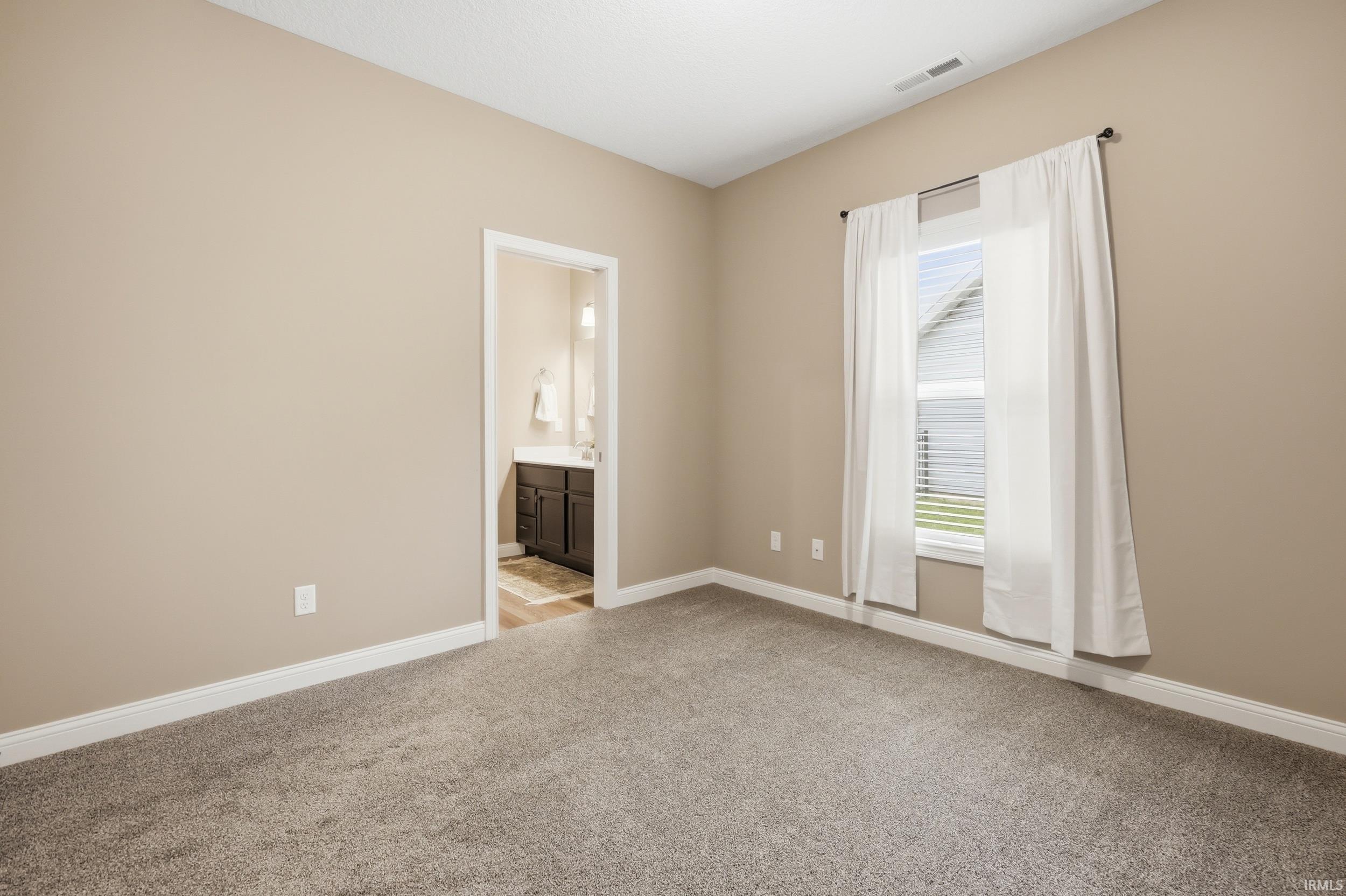 Carpeted room featuring neutral wall tones and white baseboards