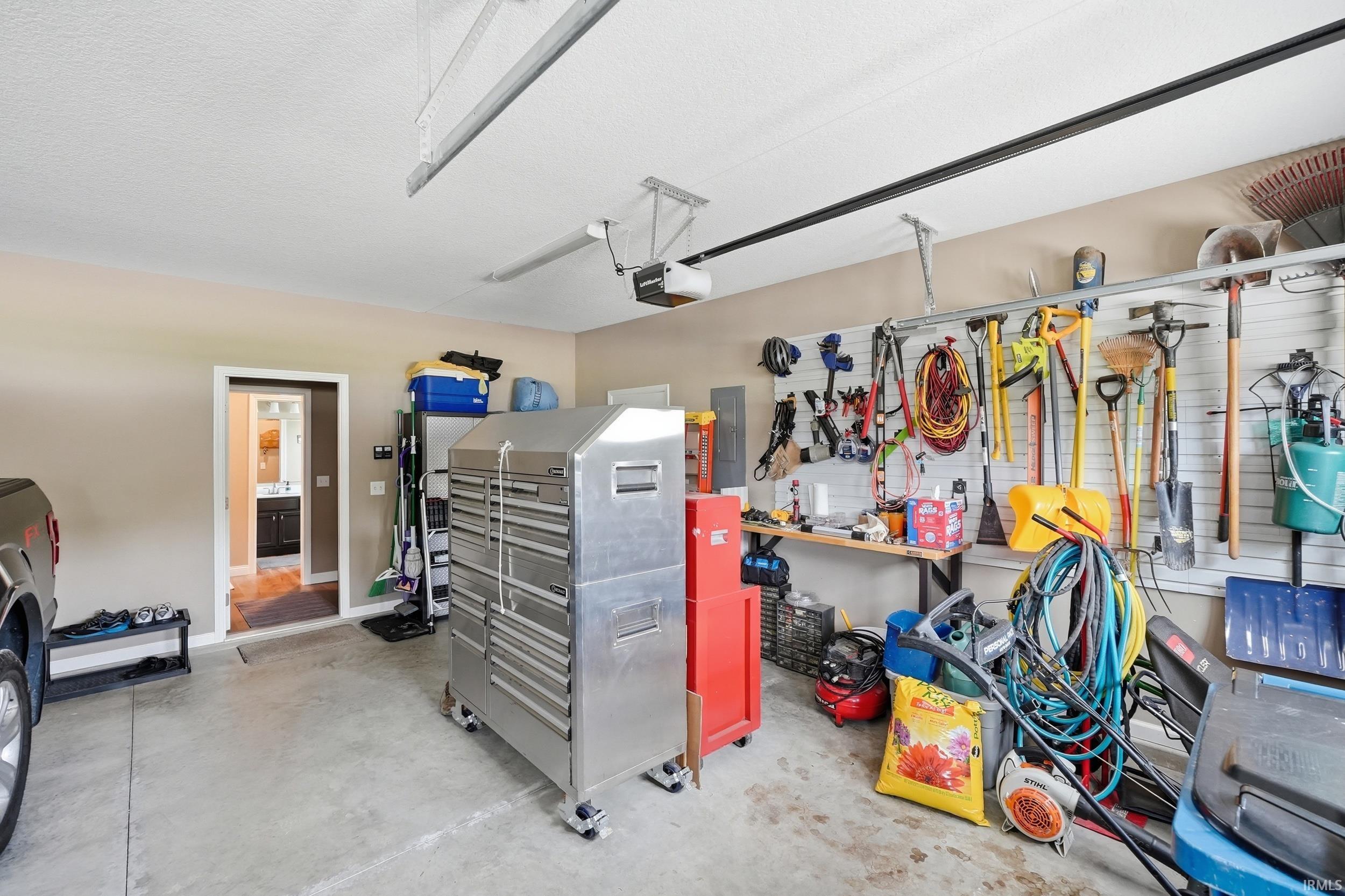 Attached garage with concrete flooring, overhead lighting, and track-mounted wall storage system