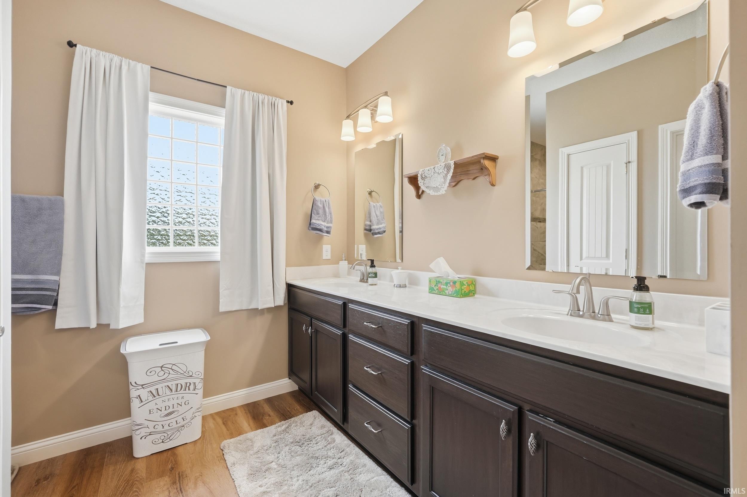 Dual vanity with dark wood-finish cabinetry, white countertops, and chrome fixtures