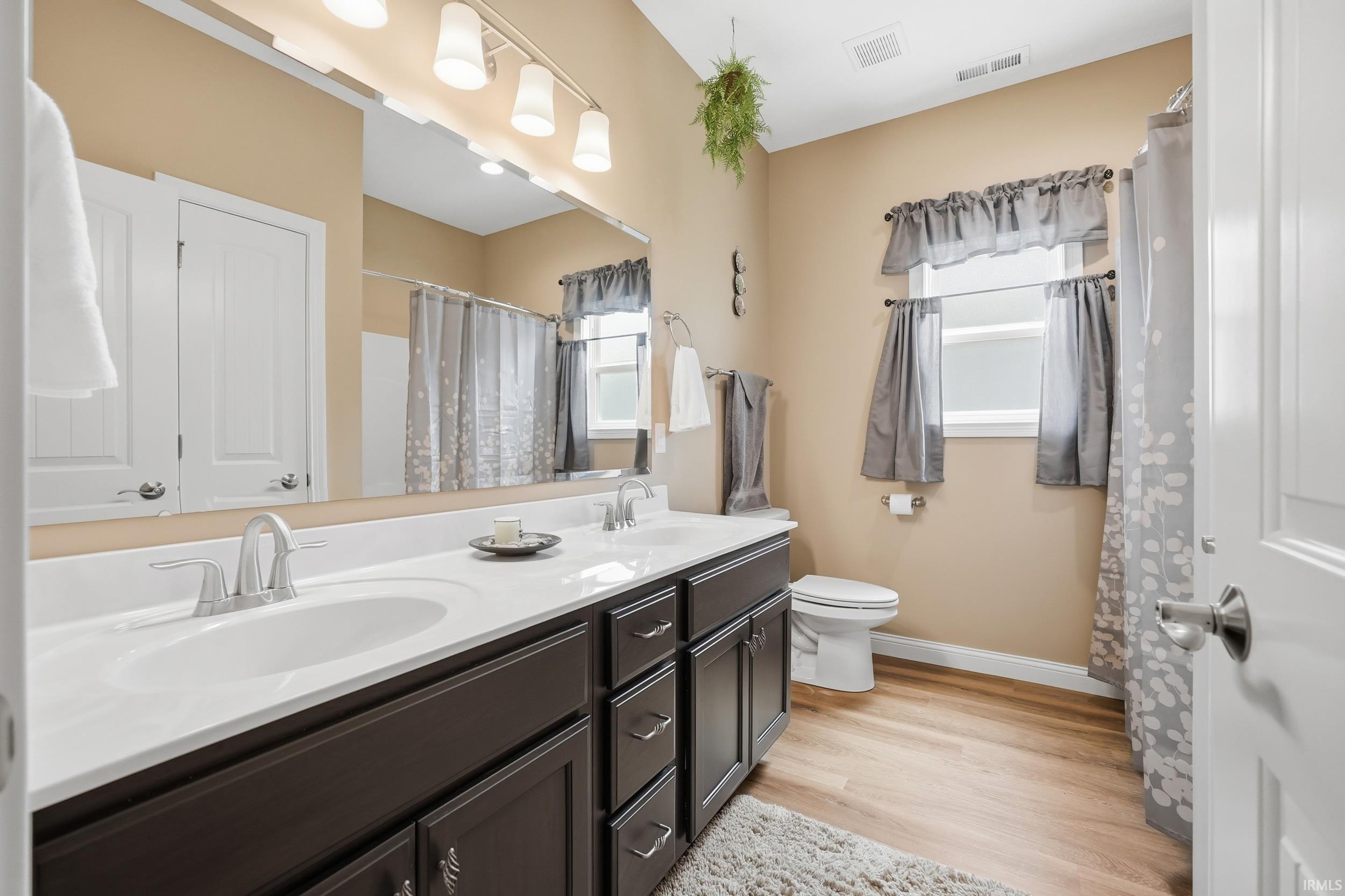 Dual sink vanity with dark wood-finish cabinetry and white countertop