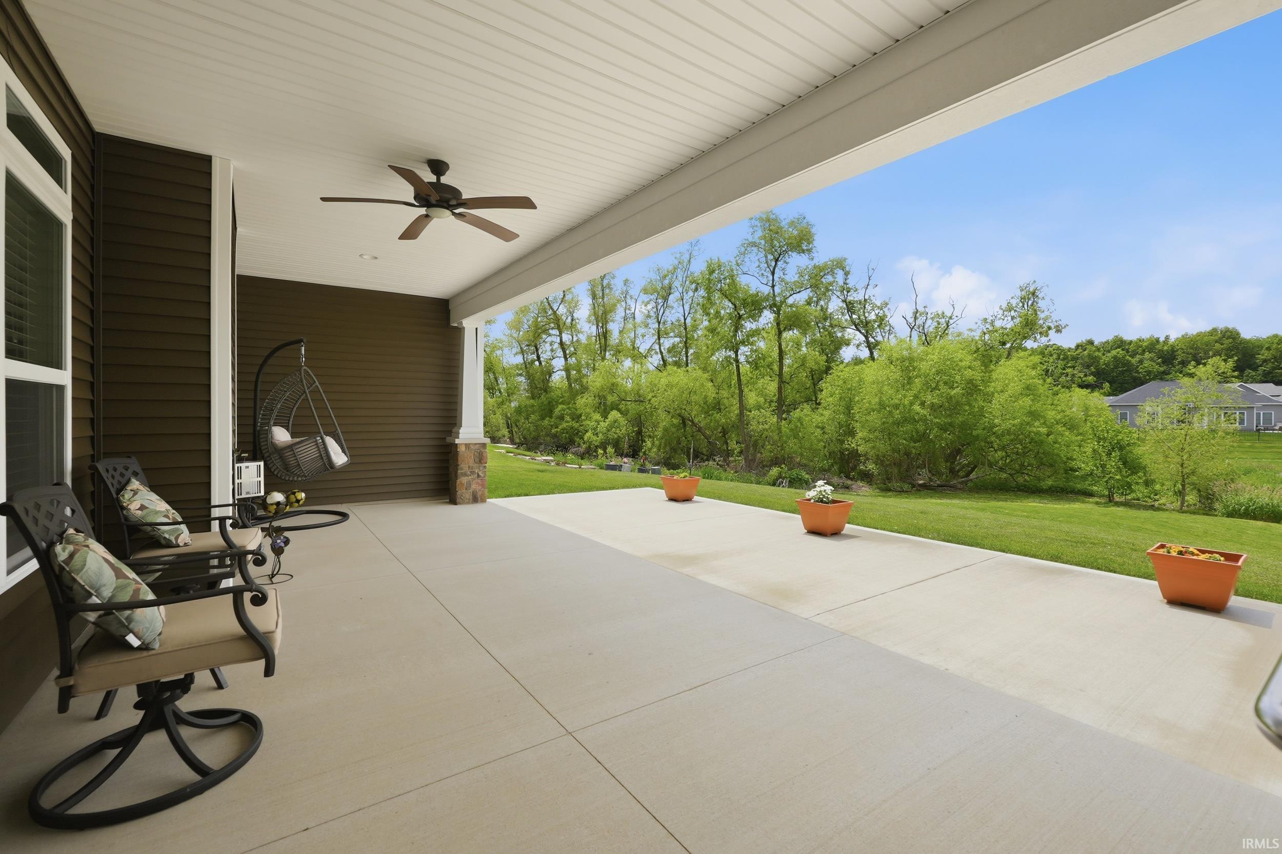 Expansive covered patio featuring a ceiling fan, planked ceiling, and a concrete surface