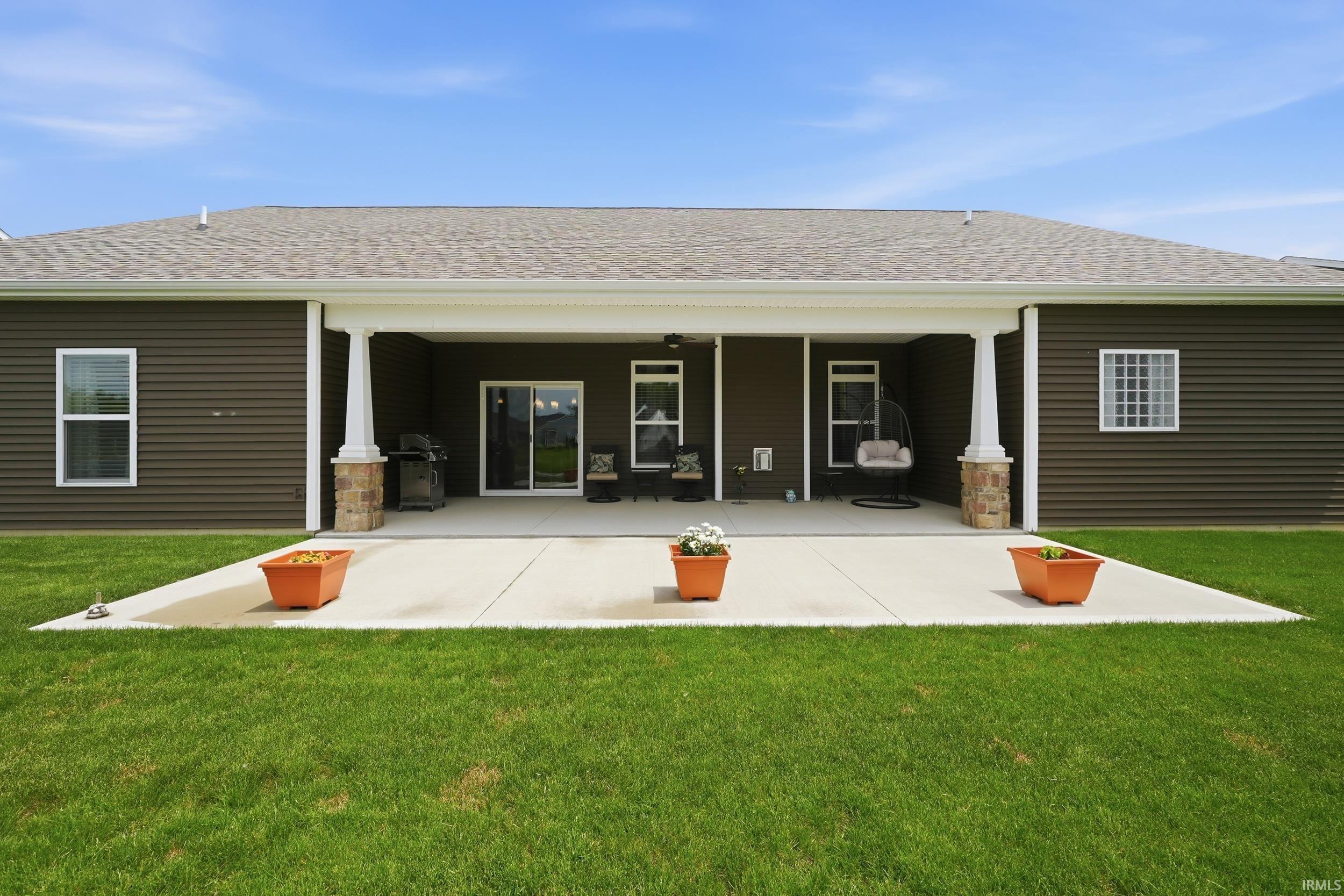 Expansive concrete patio under a covered porch, featuring white columns with stone bases