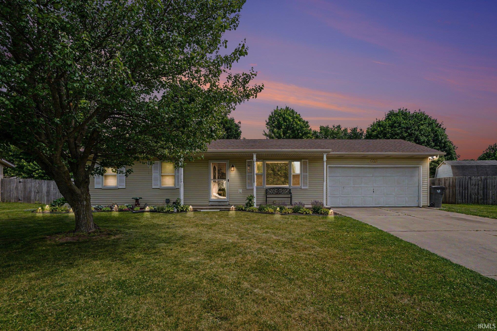 Ranch-style residence featuring light-toned horizontal siding, an attached two-car garage, and a concrete driveway