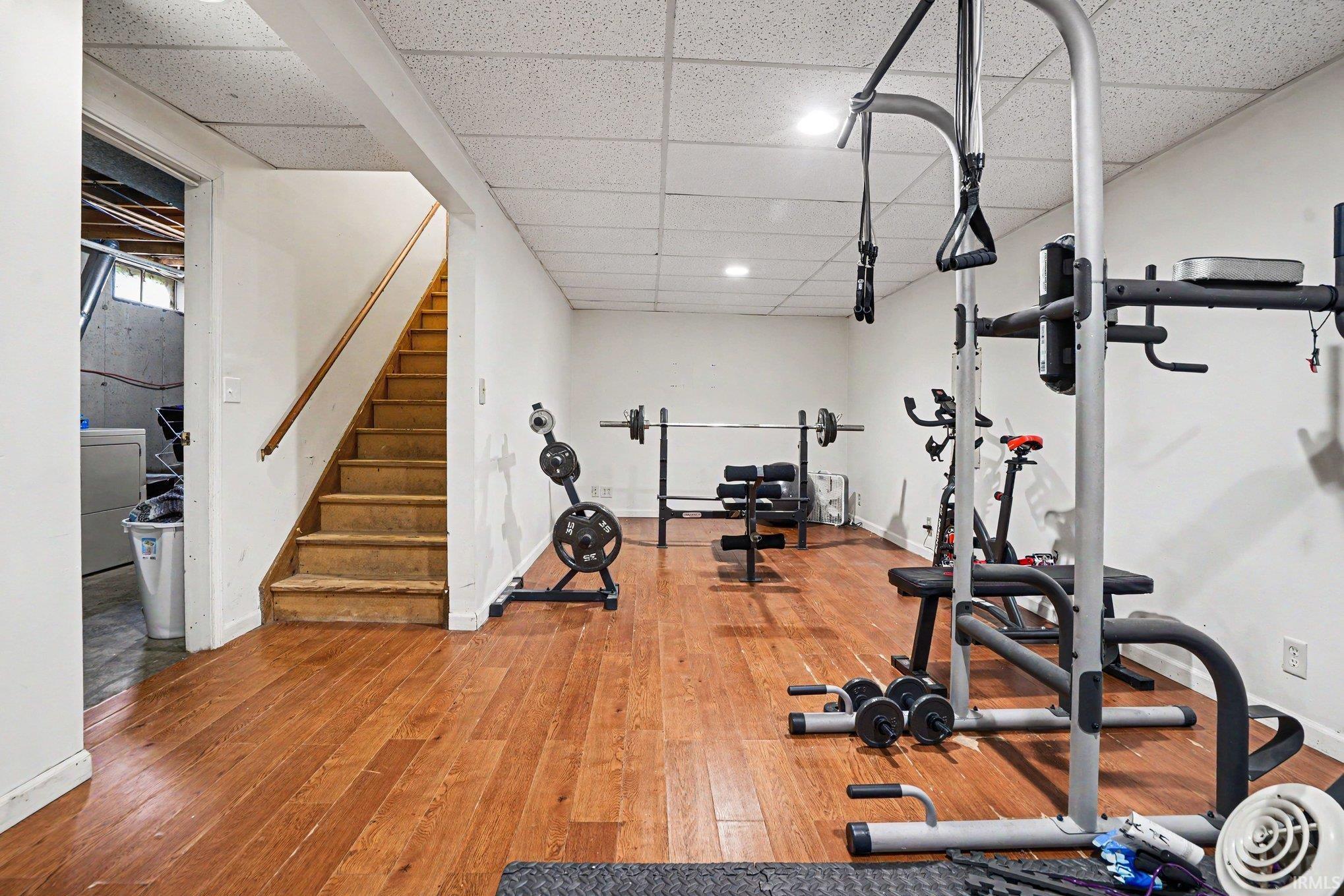 Lower level finished space featuring wood-finish flooring, white painted walls, and a drop ceiling with recessed lighting