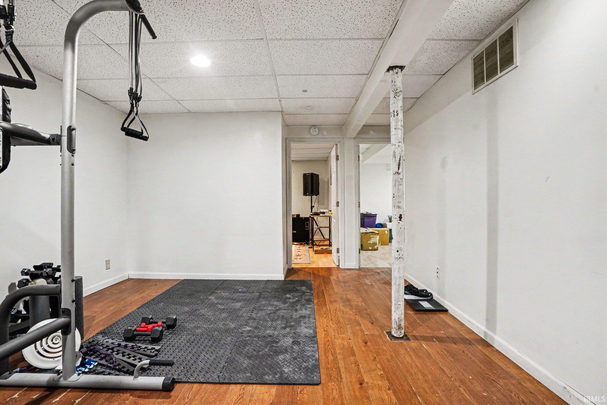 Finished lower level space featuring wood-finish flooring, white walls, and a drop ceiling