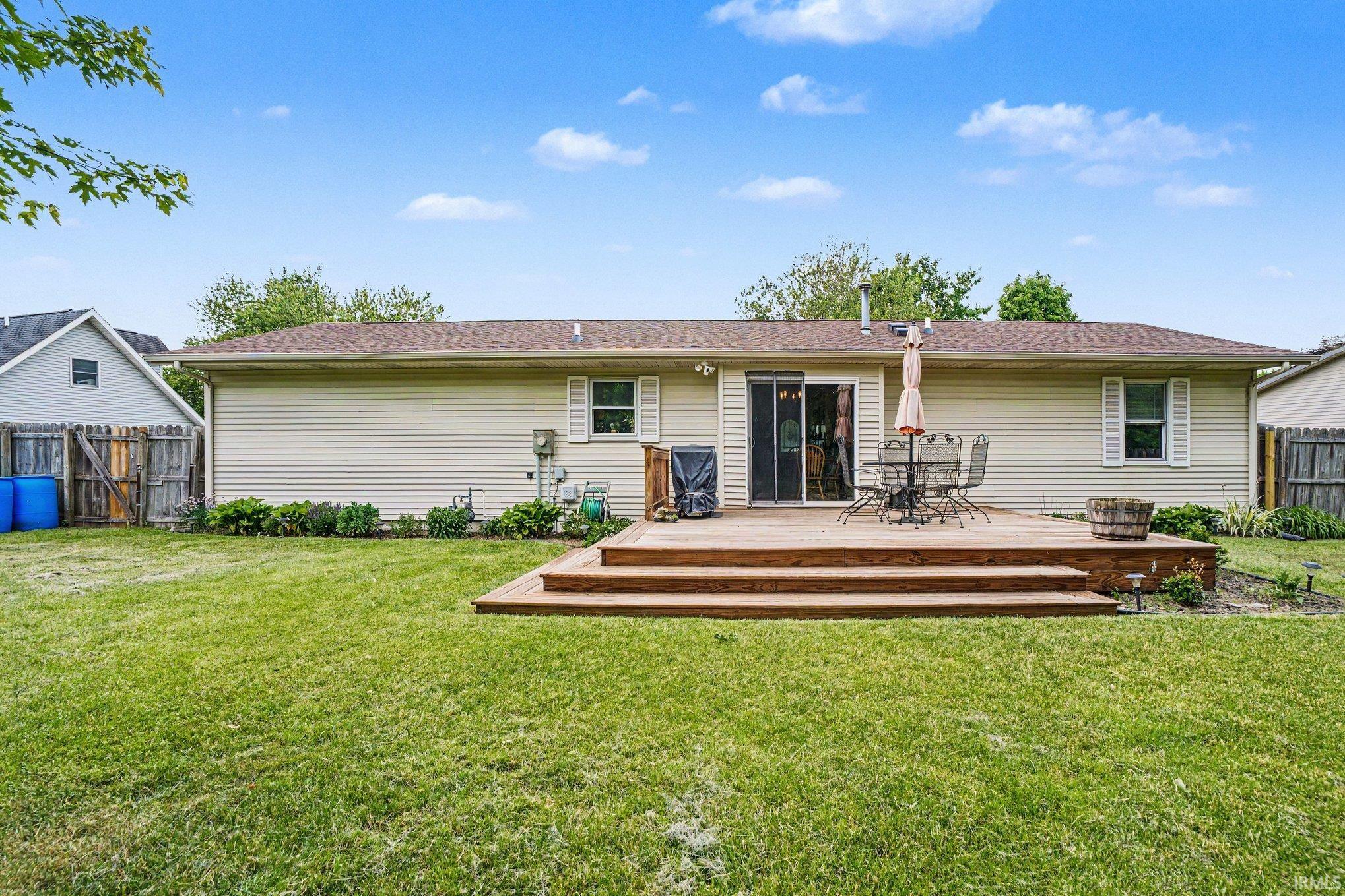 Rear exterior featuring a spacious wood deck with steps, sliding glass patio doors, and light-colored siding