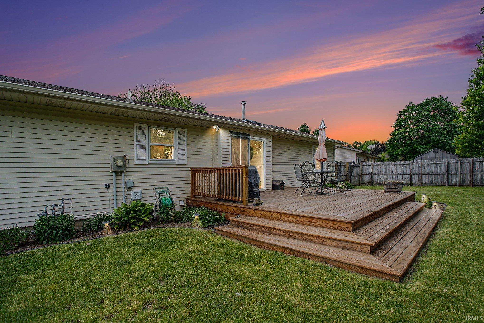 Rear exterior featuring a multi-tiered wood deck with steps to the lawn, sliding glass door access, and vinyl siding