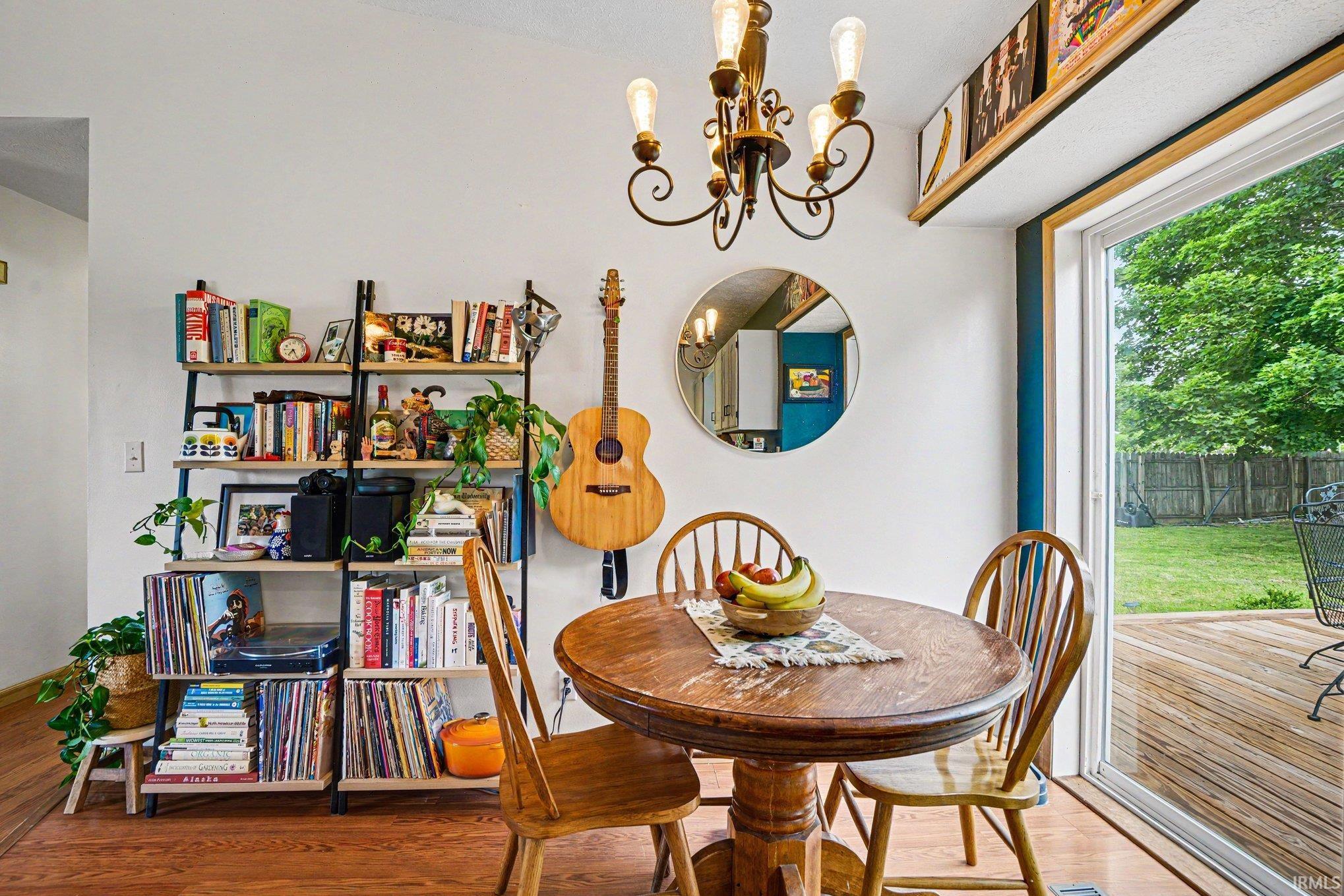 Warm wood-finish flooring complements a sliding glass door opening to an outdoor deck and green space