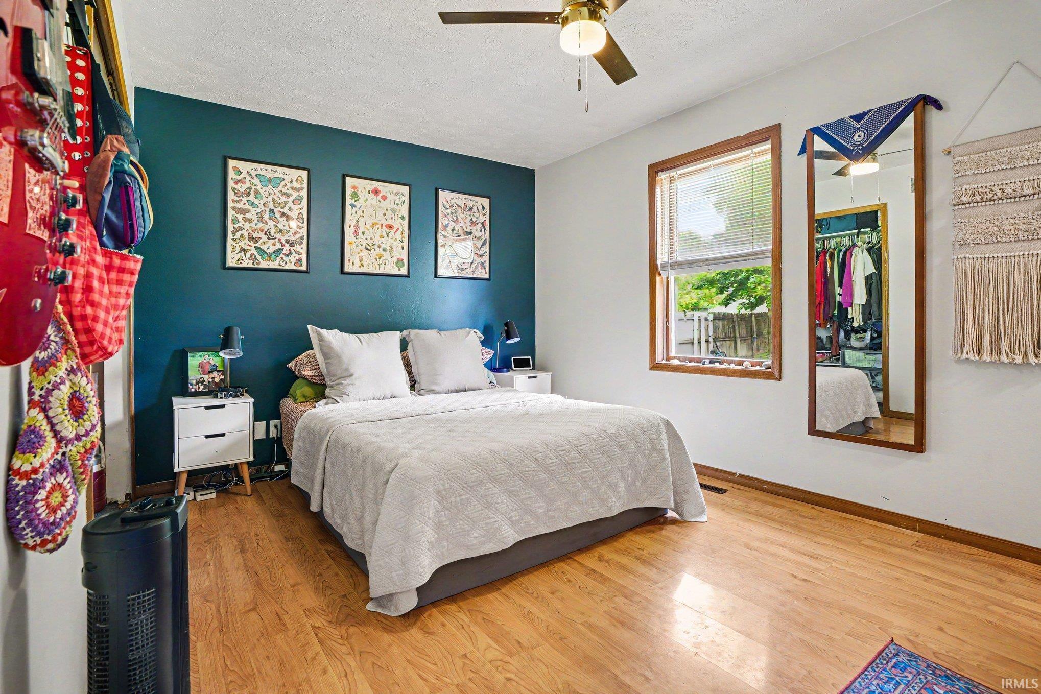 Interior room featuring wood-finish flooring, a ceiling fan with integrated lighting, and a window with wood trim
