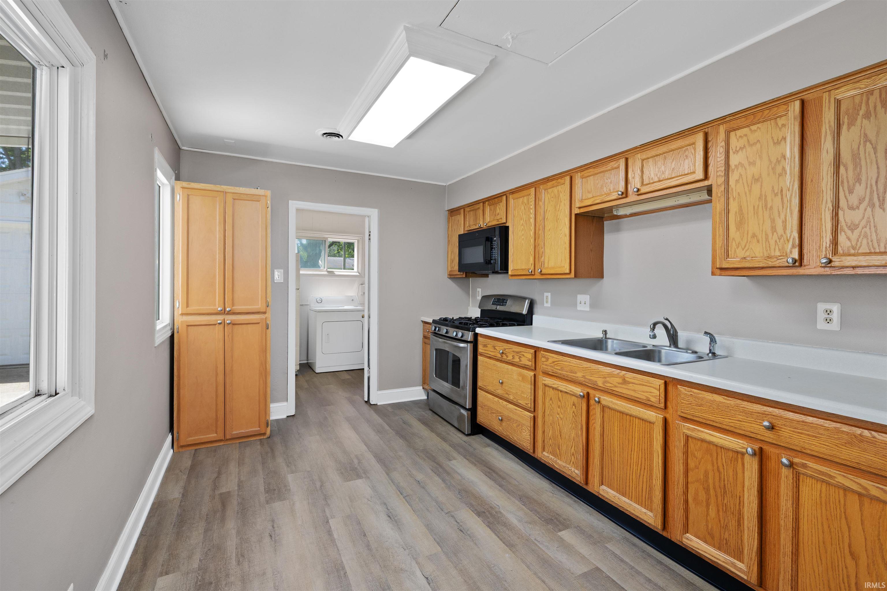 Kitchen featuring wood-finish cabinetry, stainless steel range, and a dual basin sink