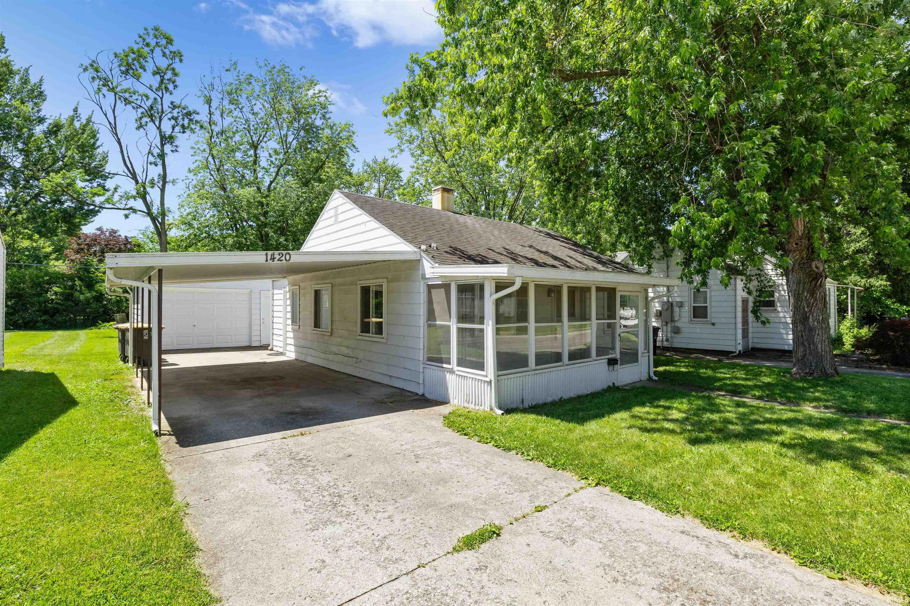 White exterior featuring a carport, screened-in porch, and asphalt shingle roof