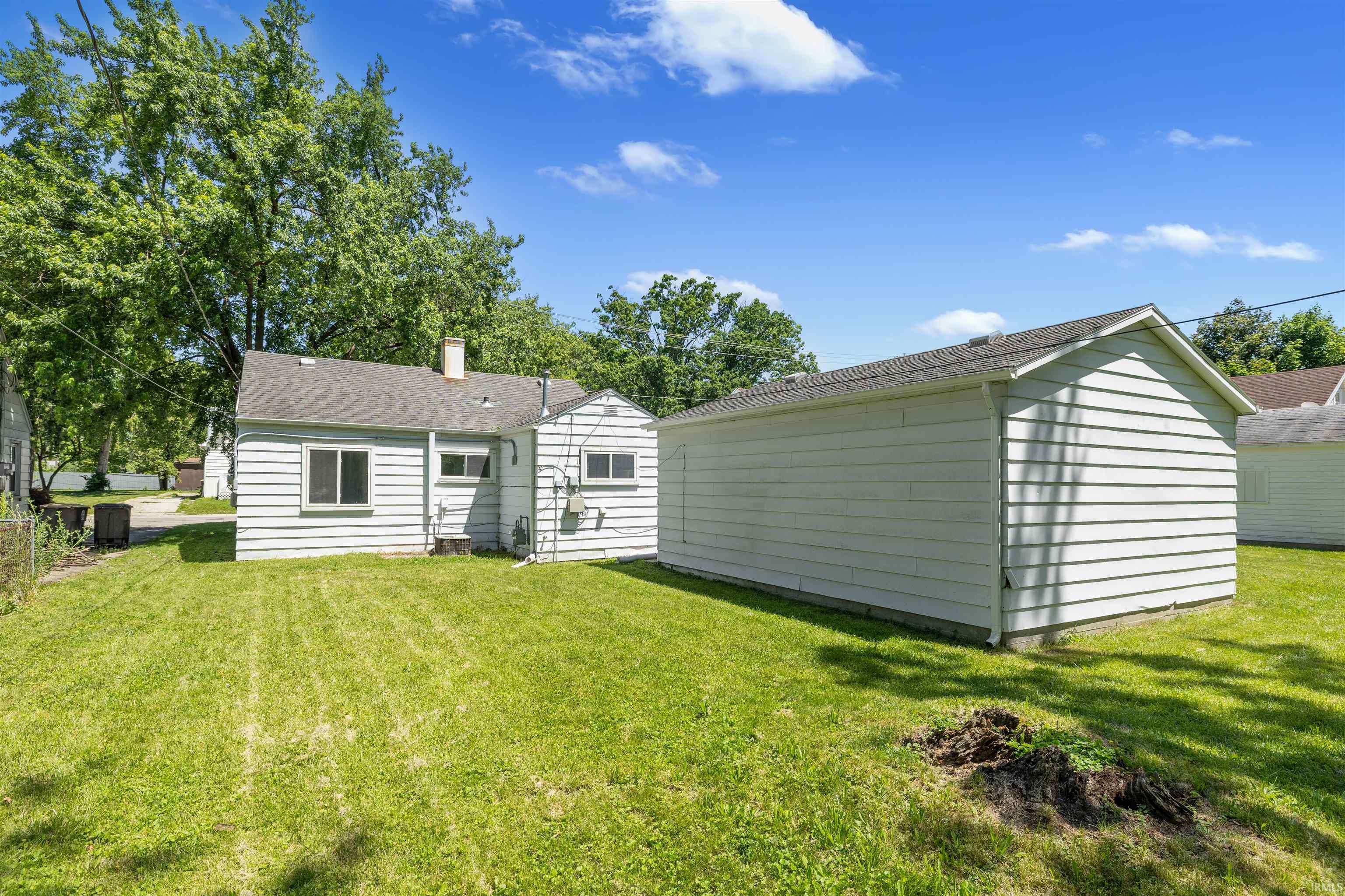 Expansive grassy yard with a detached garage featuring white siding and an asphalt shingle roof