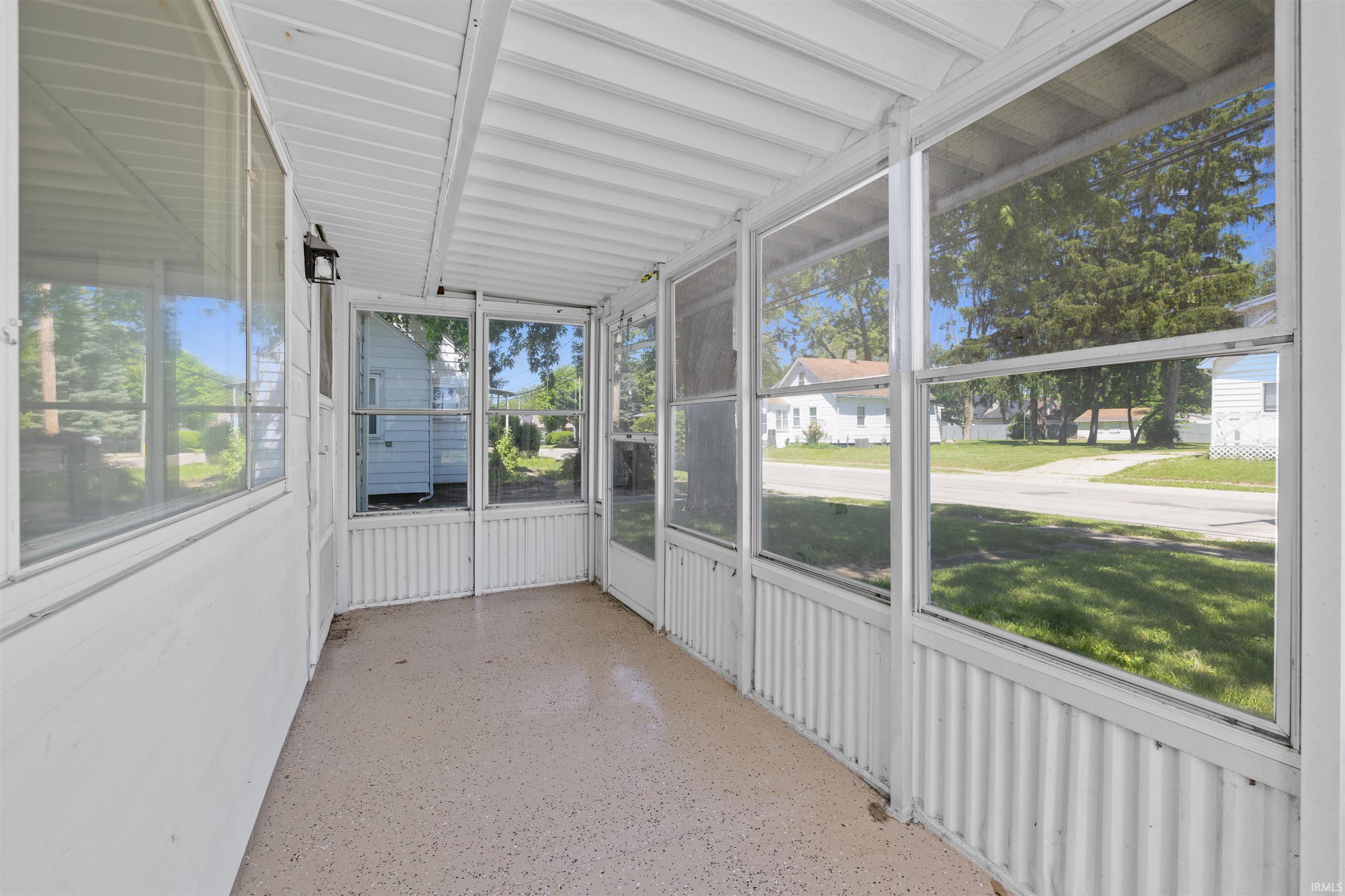 Screened porch featuring a textured floor, white aluminum framing, and a ceiling-mounted light fixture