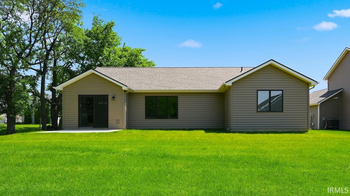 Expansive green lawn with a tan siding exterior and a light gray shingle roof