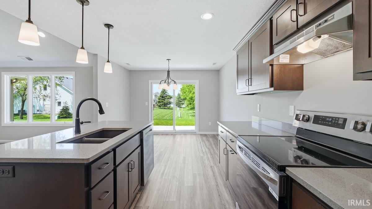 Modern kitchen featuring a large island with a double basin sink and pendant lighting
