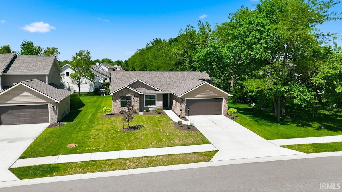 Ranch-style residence featuring a brick facade, attached two-car garage with a dark wood-finish door, and a spacious concrete driveway