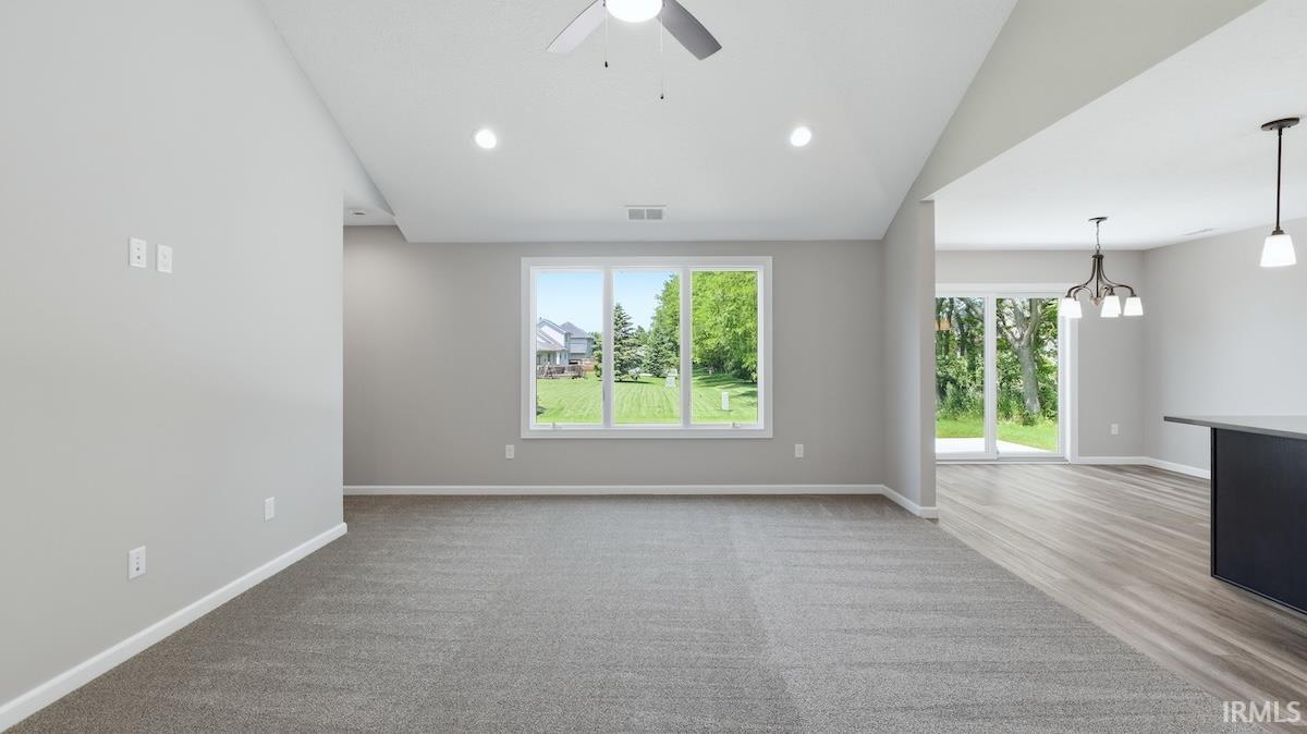 Carpeted living area with vaulted ceiling, recessed lighting, and a ceiling fan