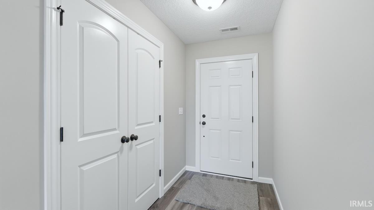 Entryway with white panel doors, matte black hardware, wood-finish flooring, and recessed lighting