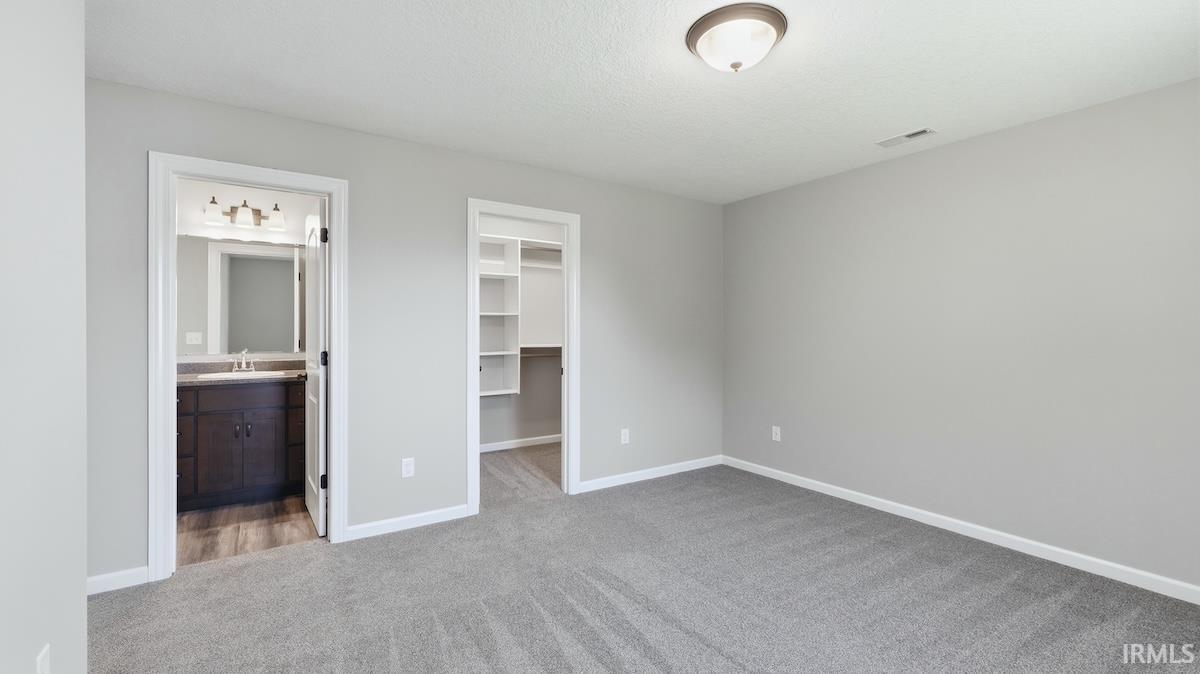 Spacious room featuring neutral carpeting, light gray walls, and white trim