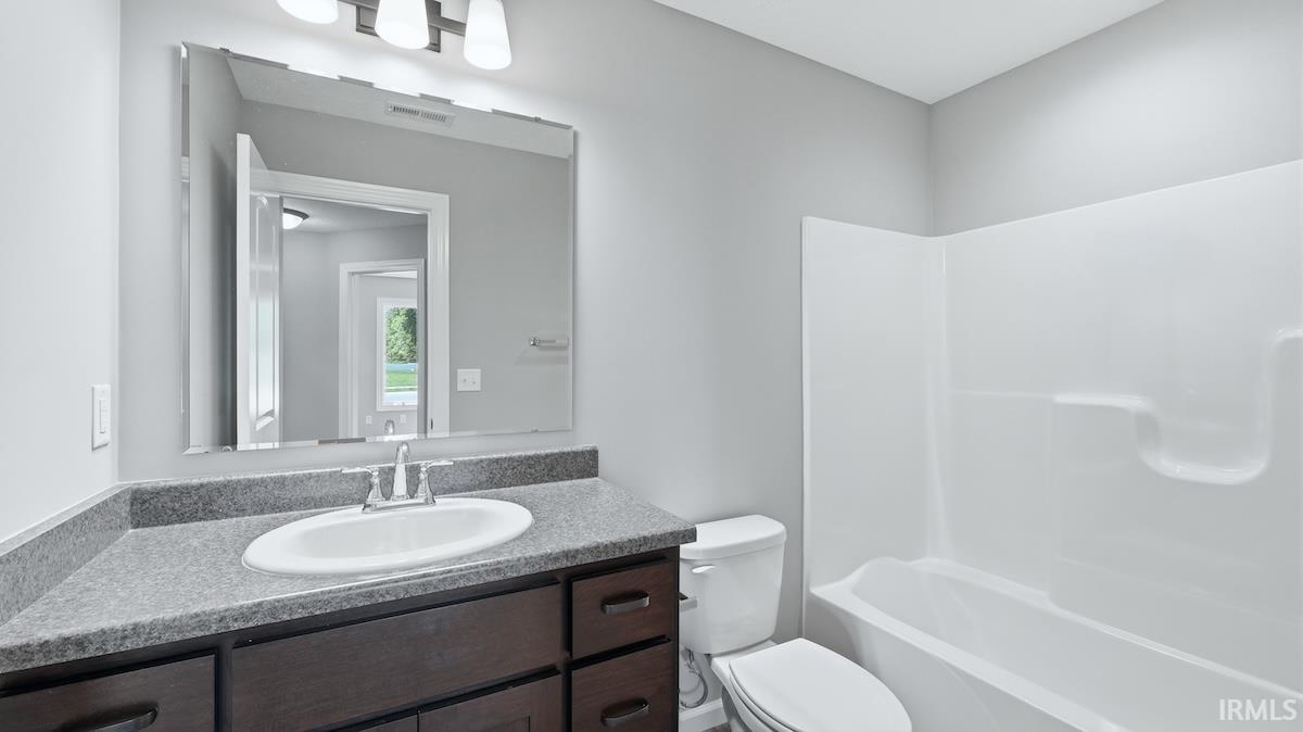 Bathroom featuring a dark wood-finish vanity with an integrated sink, a gray countertop, and a white tub-shower combination