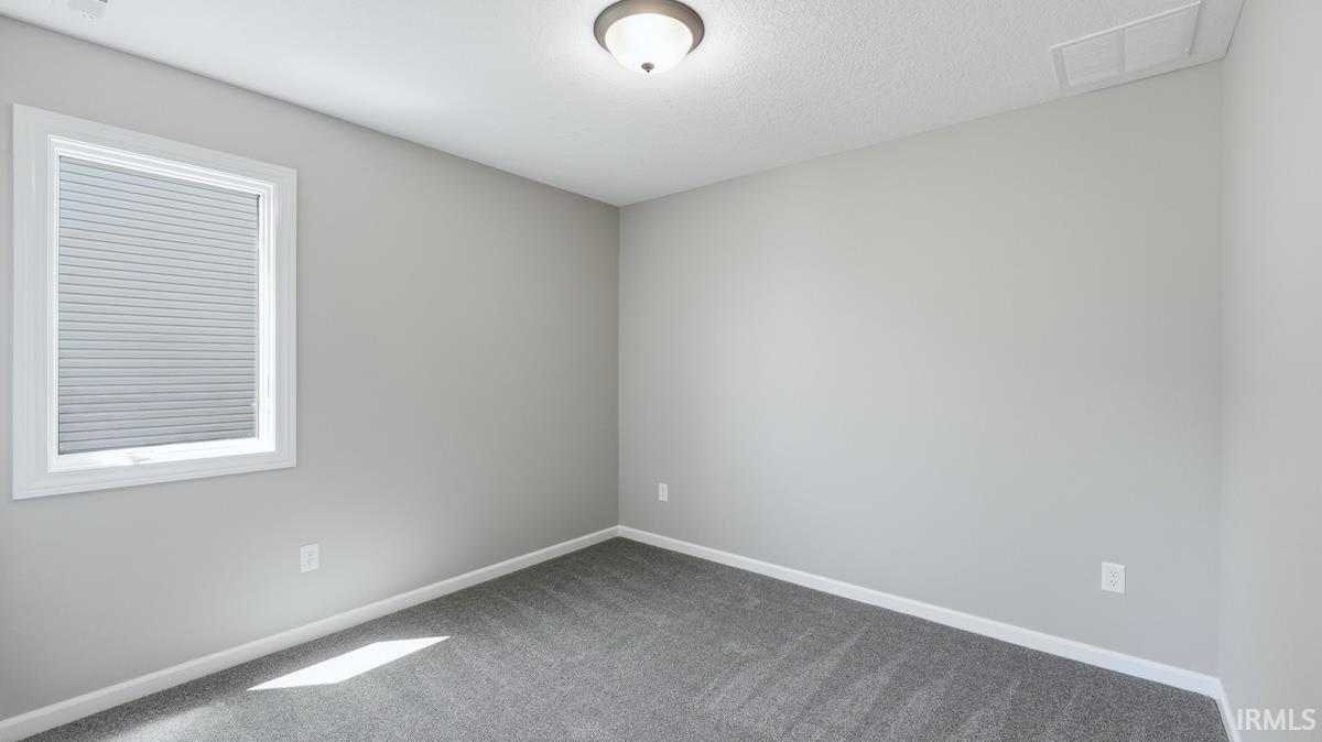 Neutral-toned room featuring a single window with white trim, cellular blinds, and a flush-mount ceiling light fixture
