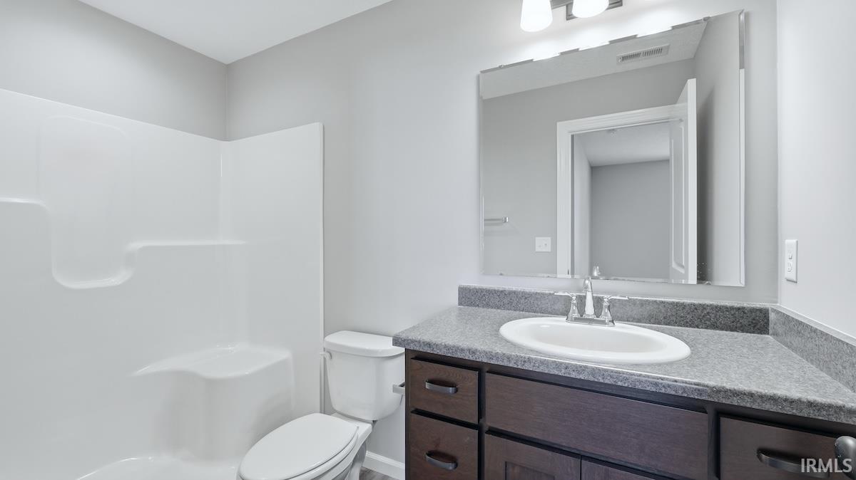 Bathroom featuring a dark wood-finish vanity with a light gray countertop, white oval sink, and a large wall-mounted mirror