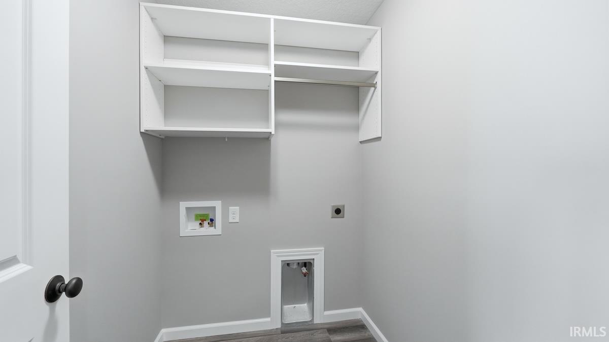 Dedicated laundry area featuring white wall cabinetry, integrated hanging rod, and wood-finish flooring
