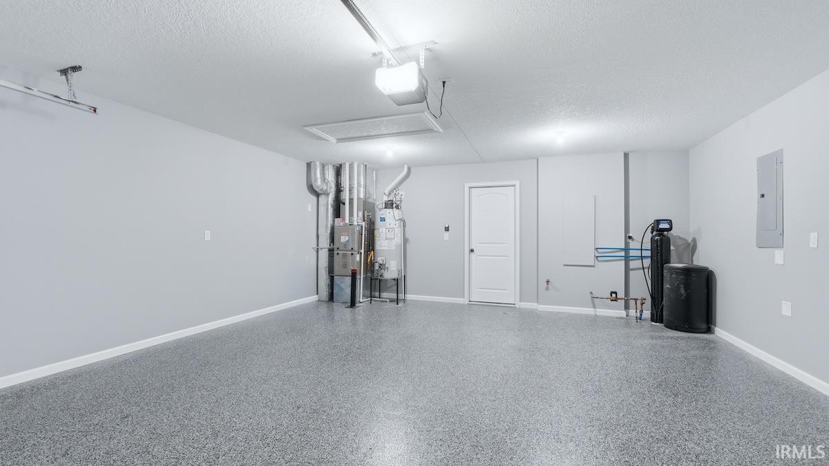Spacious garage featuring a durable epoxy-flake flooring, neutral painted walls, exposed ductwork, and ceiling-mounted lighting