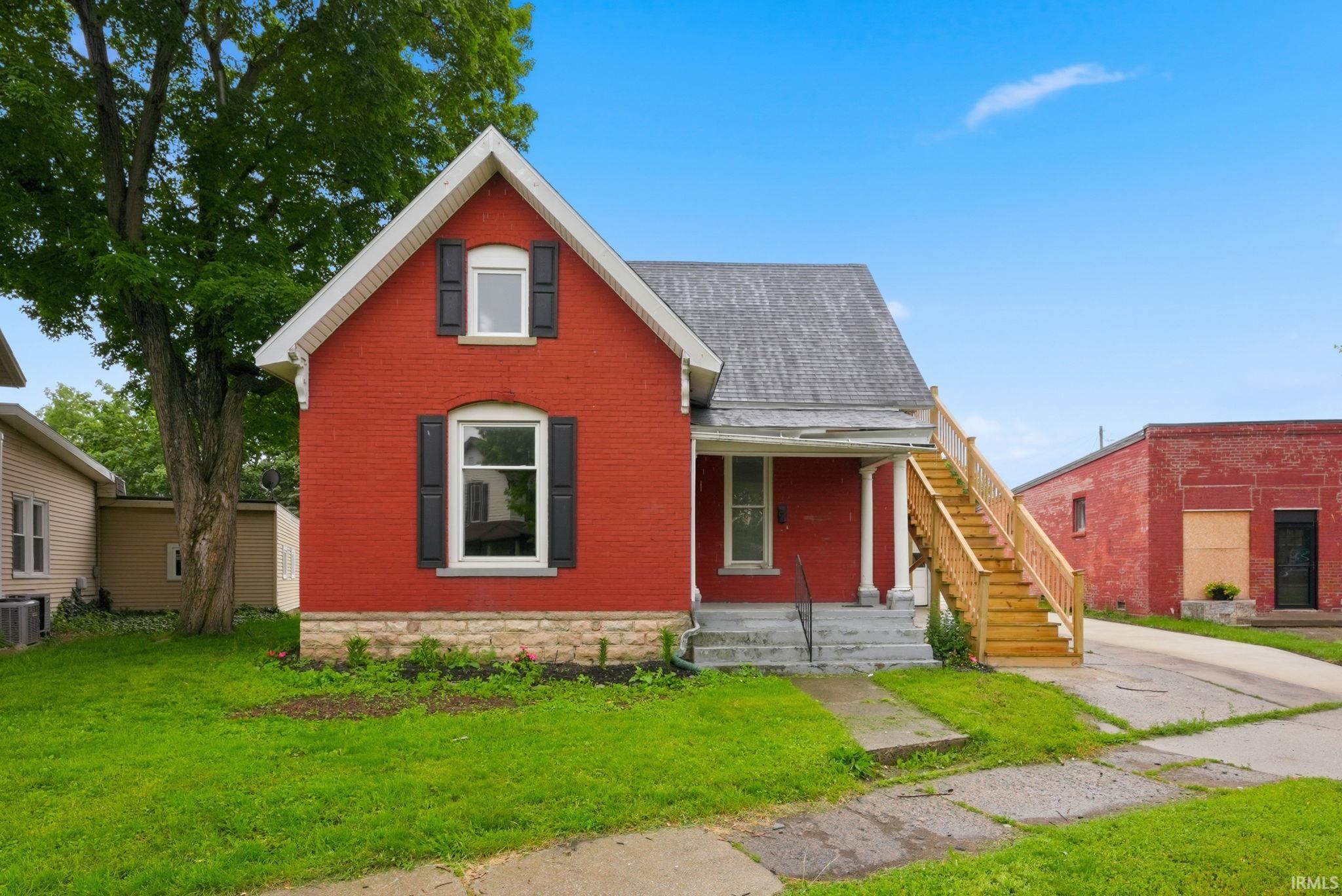 Red brick exterior with white trim, featuring a gabled roofline and dark window shutters