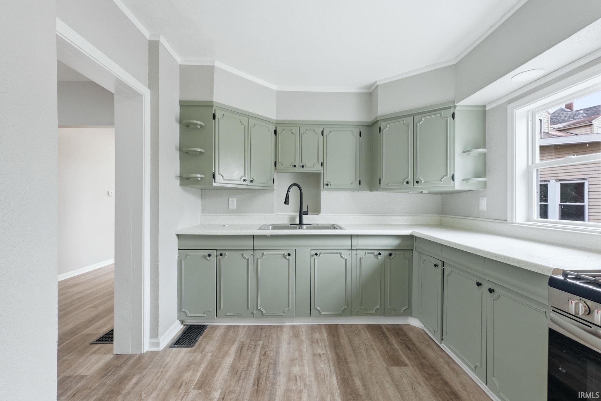 Kitchen featuring green cabinetry, white countertops, wood-finish flooring, and a stainless steel oven
