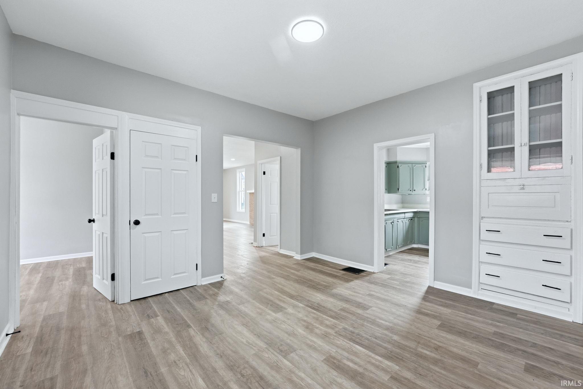 Spacious interior featuring wood-finish flooring, light grey wall paint, and white trim