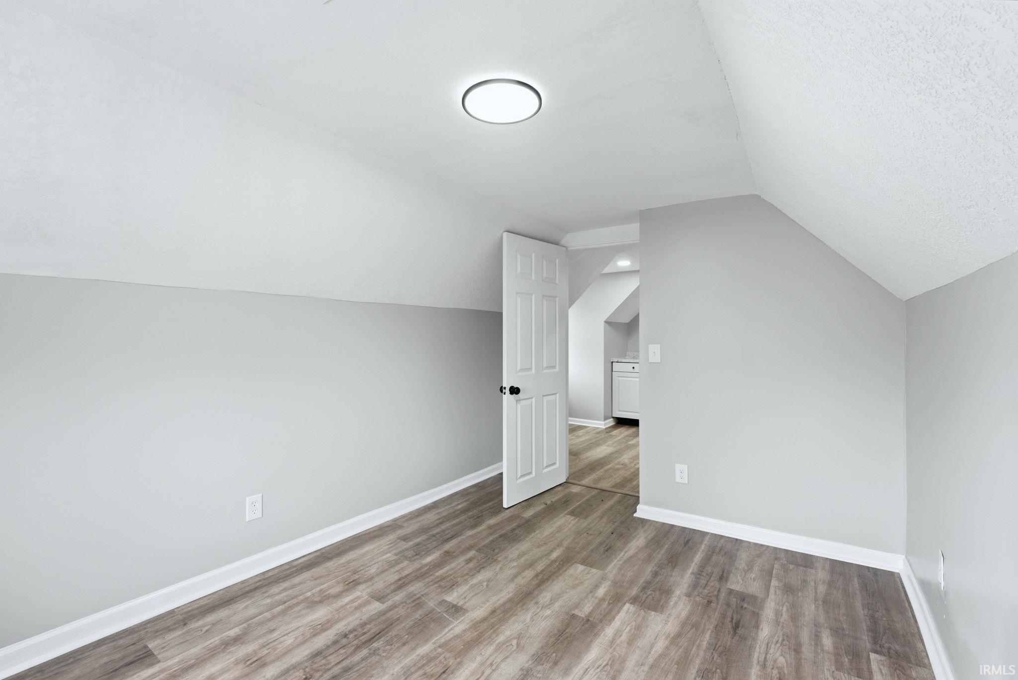 Room featuring wood-finish flooring, light grey painted walls, white trim, and a flush mount ceiling light